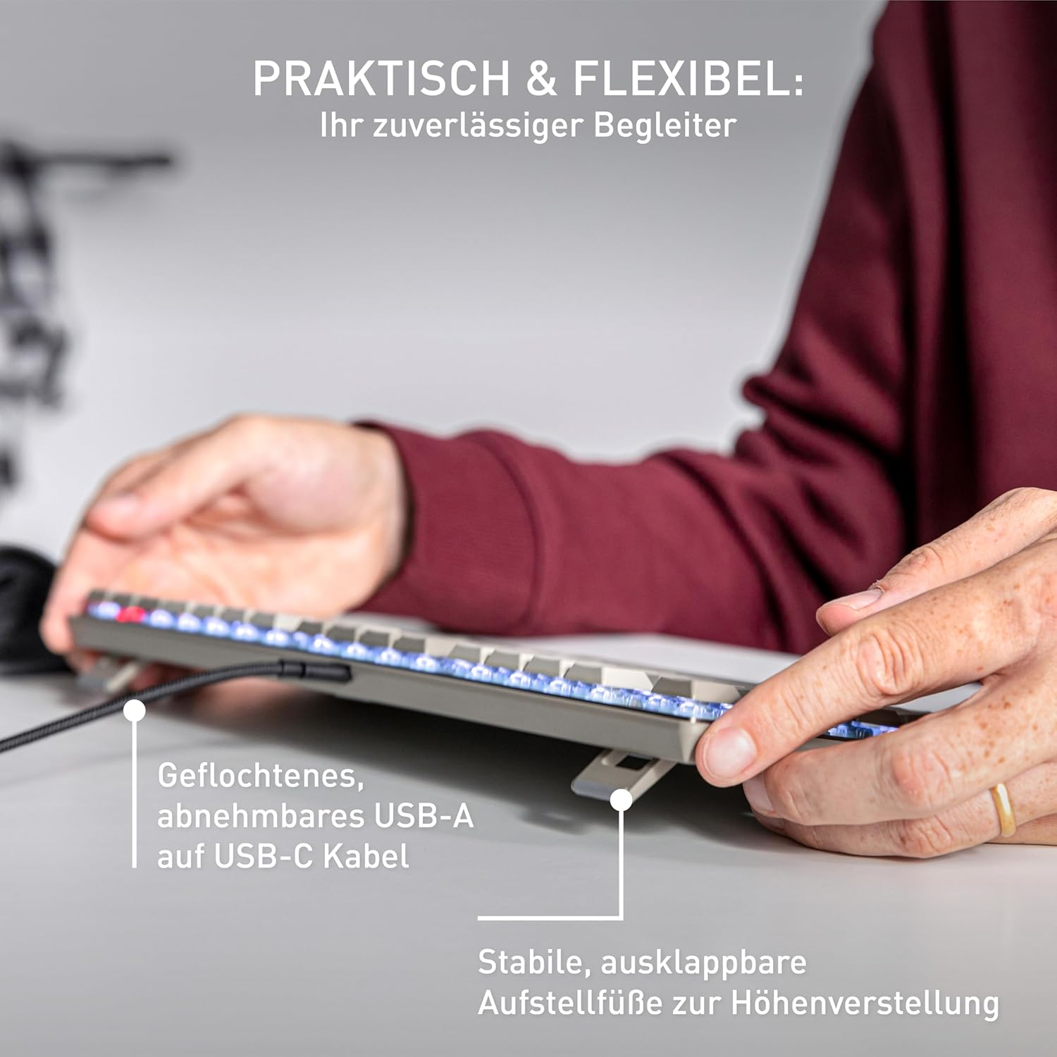Hände benutzen eine Tastatur. Geflochtenes USB-A-zu-USB-C-Kabel. Stabile, klappbare Füße zur Höhenverstellung.