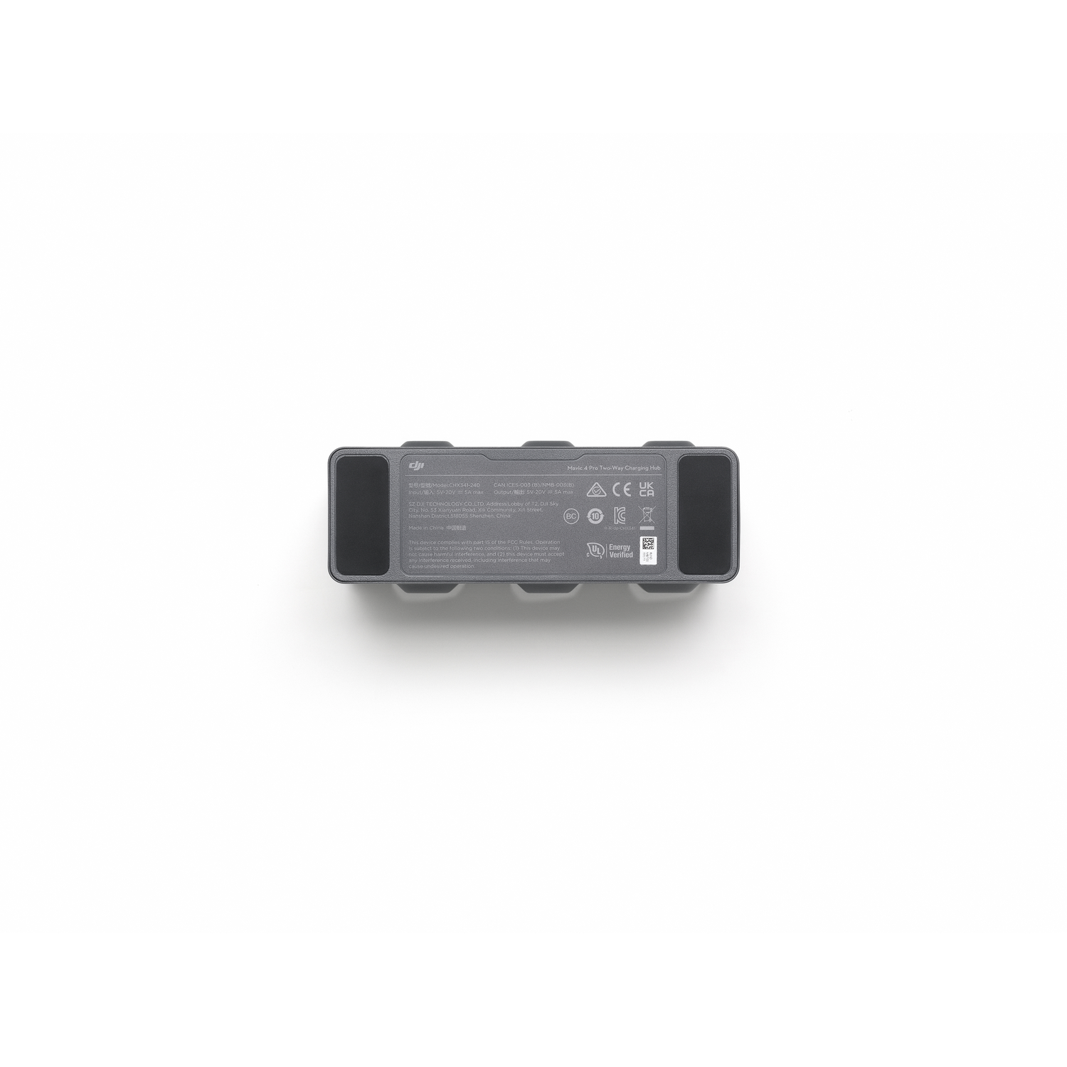 A gray drone battery lies on a white surface. It has a number of labels and ports. The background is white.