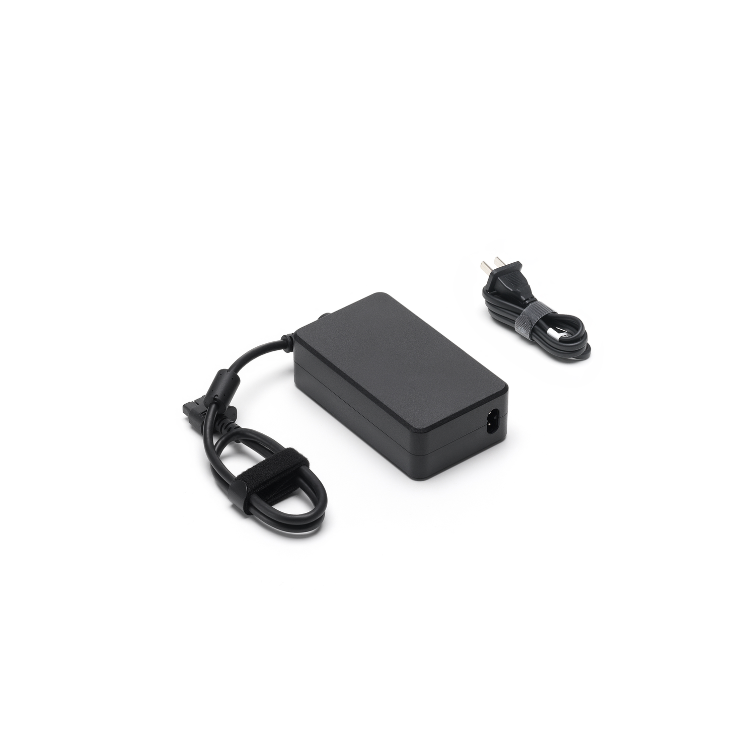 A black power adapter and its cable, with a plug. It is on a white surface.
