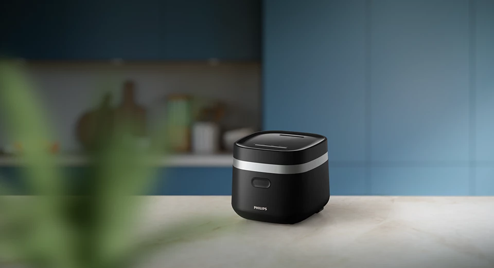 Egy fekete Philips rizsfőző egy fehér márvány pulton a konyhában.