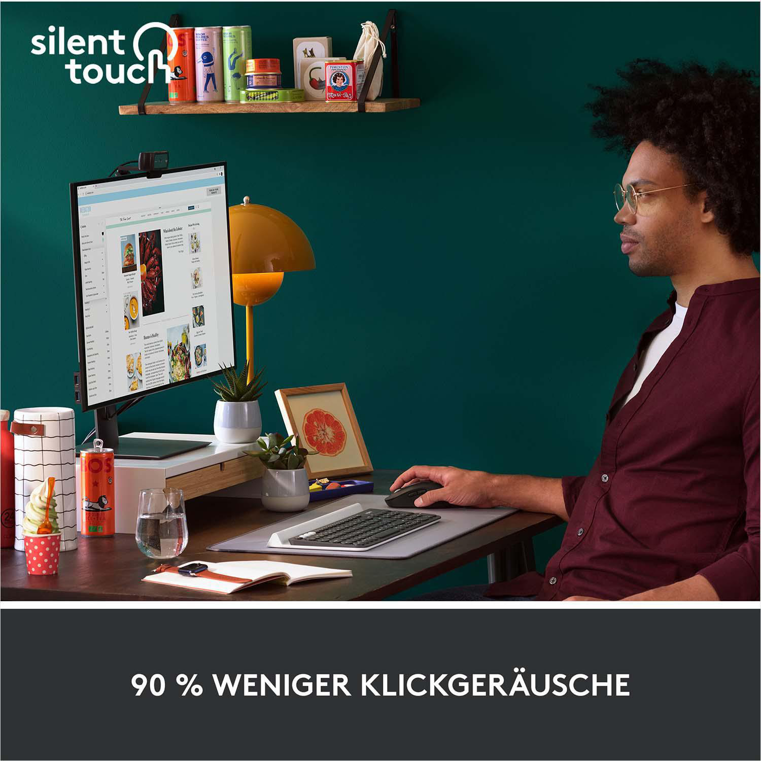 Mann benutzt schwarze Maus, Tastatur und Computer an einem Schreibtisch mit Lampe.
