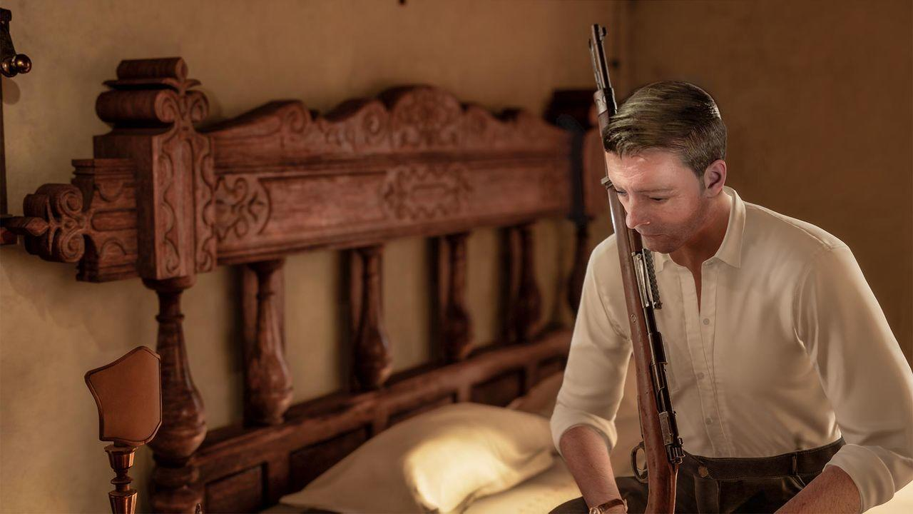 Ein Mann sitzt auf einem Bett mit einem Gewehr, mit einem hölzernen Kopfteil dahinter.