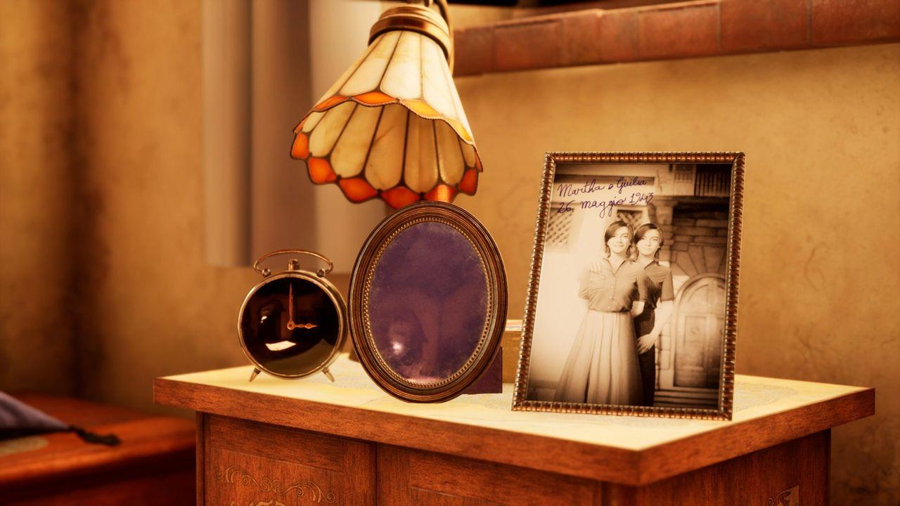 Ein Tisch mit einer Lampe, einem gerahmten Foto und einem Wecker.
