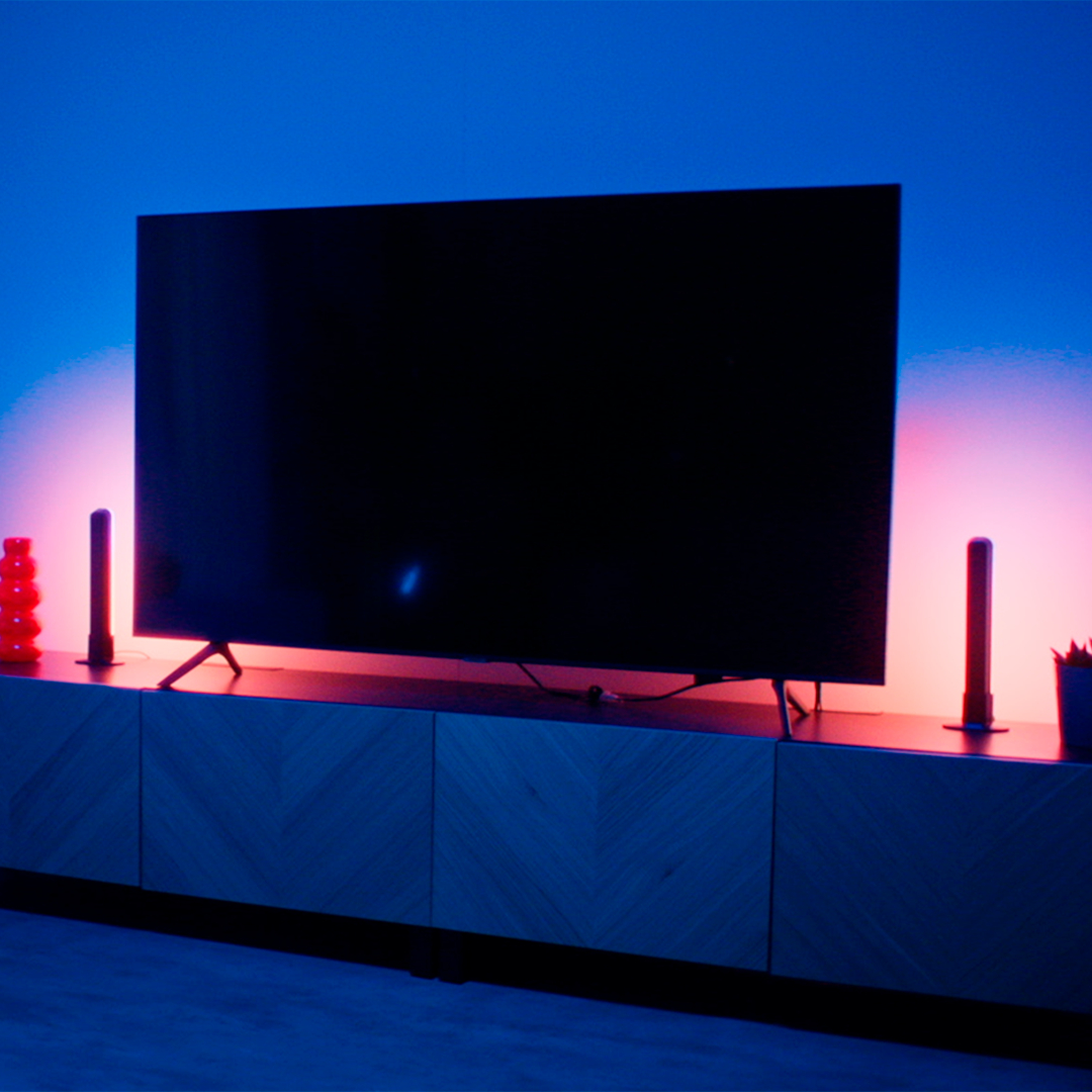 Fernseher auf Holzschrank, mit blauem und rosa Licht.