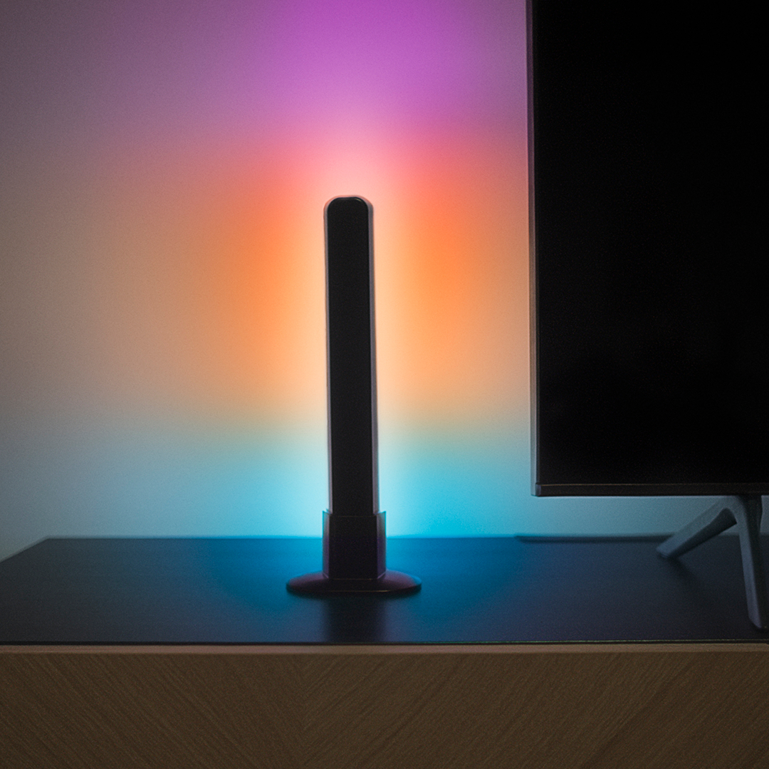 Eine Lichtleiste mit Farbverläufen. Steht auf einem Tisch mit buntem Hintergrund.