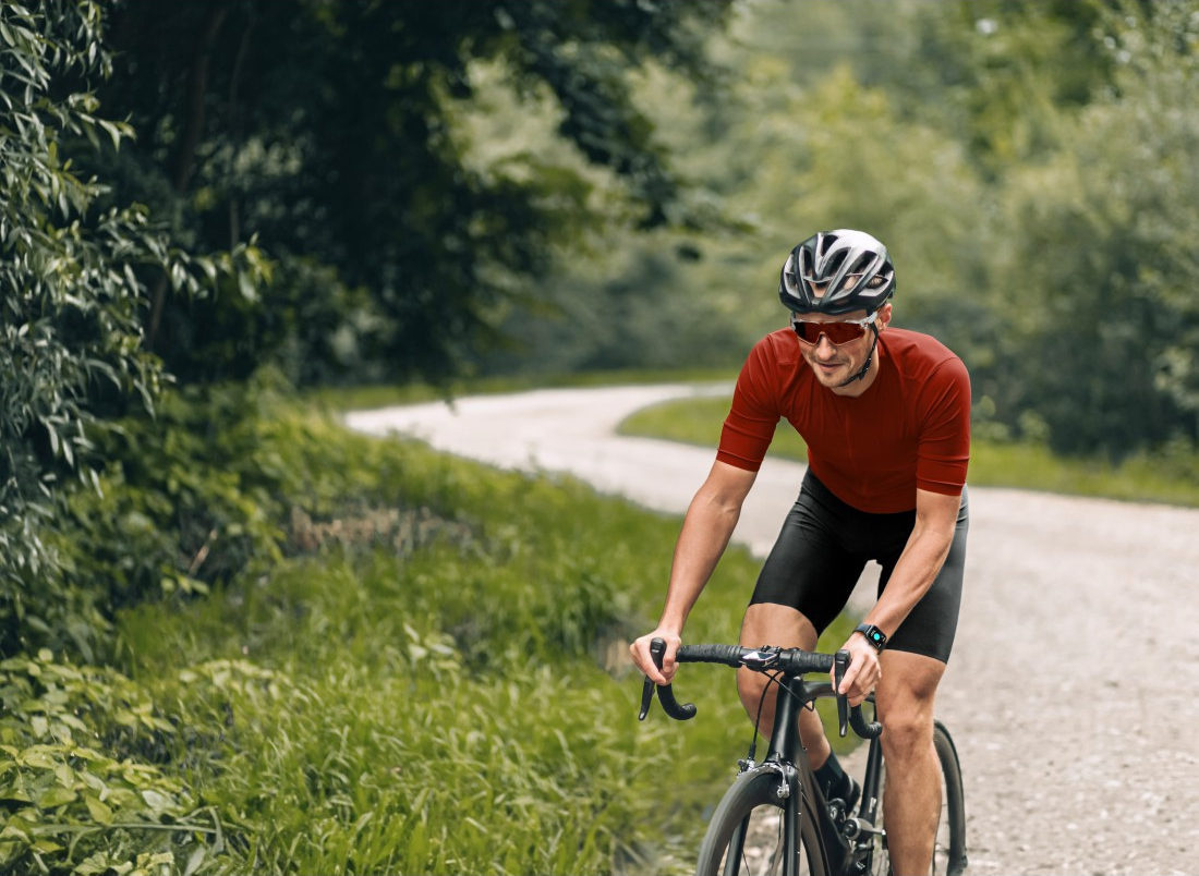 Radfahrer auf einer Schotterstraße durch ein von Bäumen gesäumtes Gebiet.