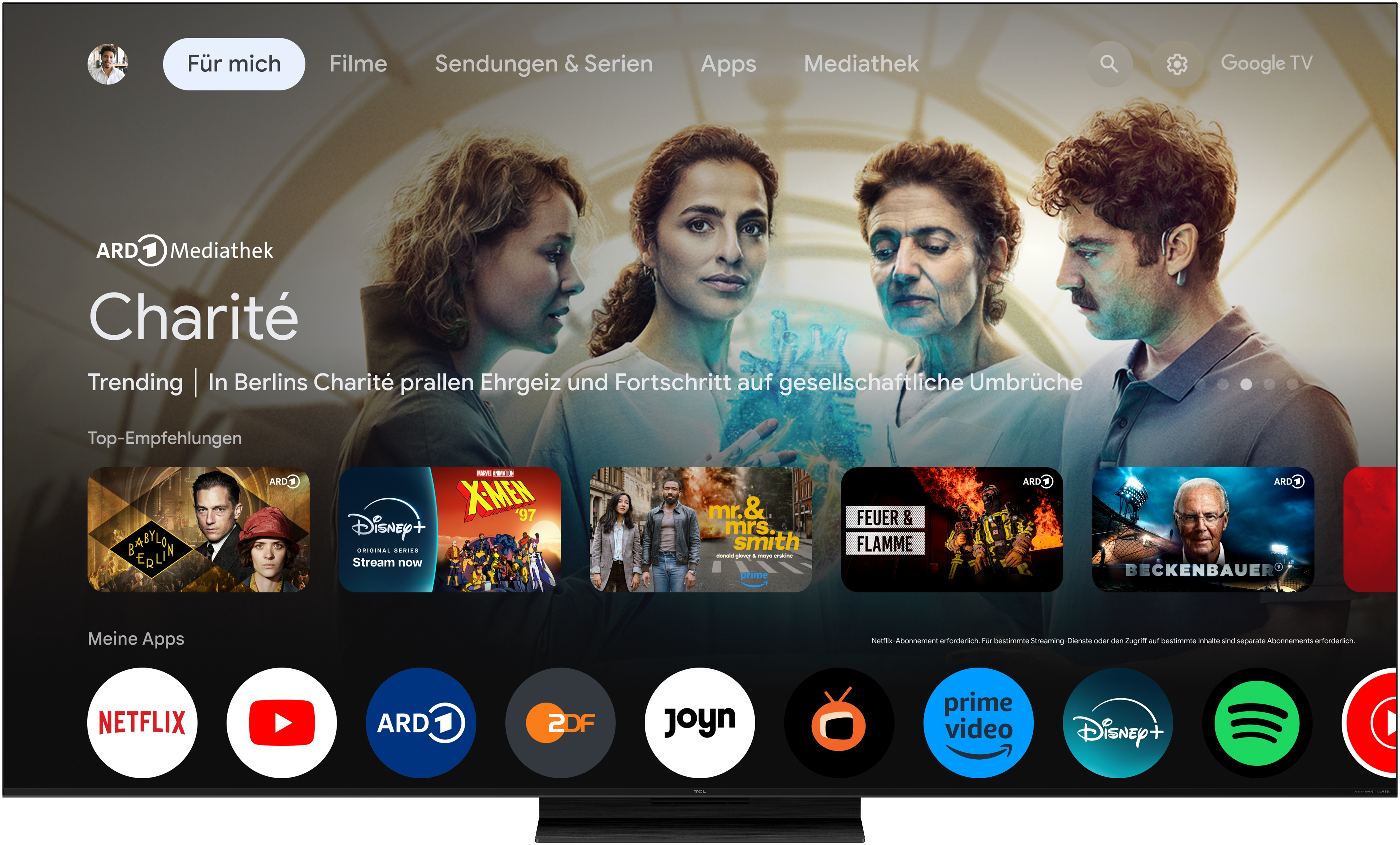 Ein TCL-Fernseher mit einer Medienoberfläche mit deutschem Text und einem Google TV-Logo.