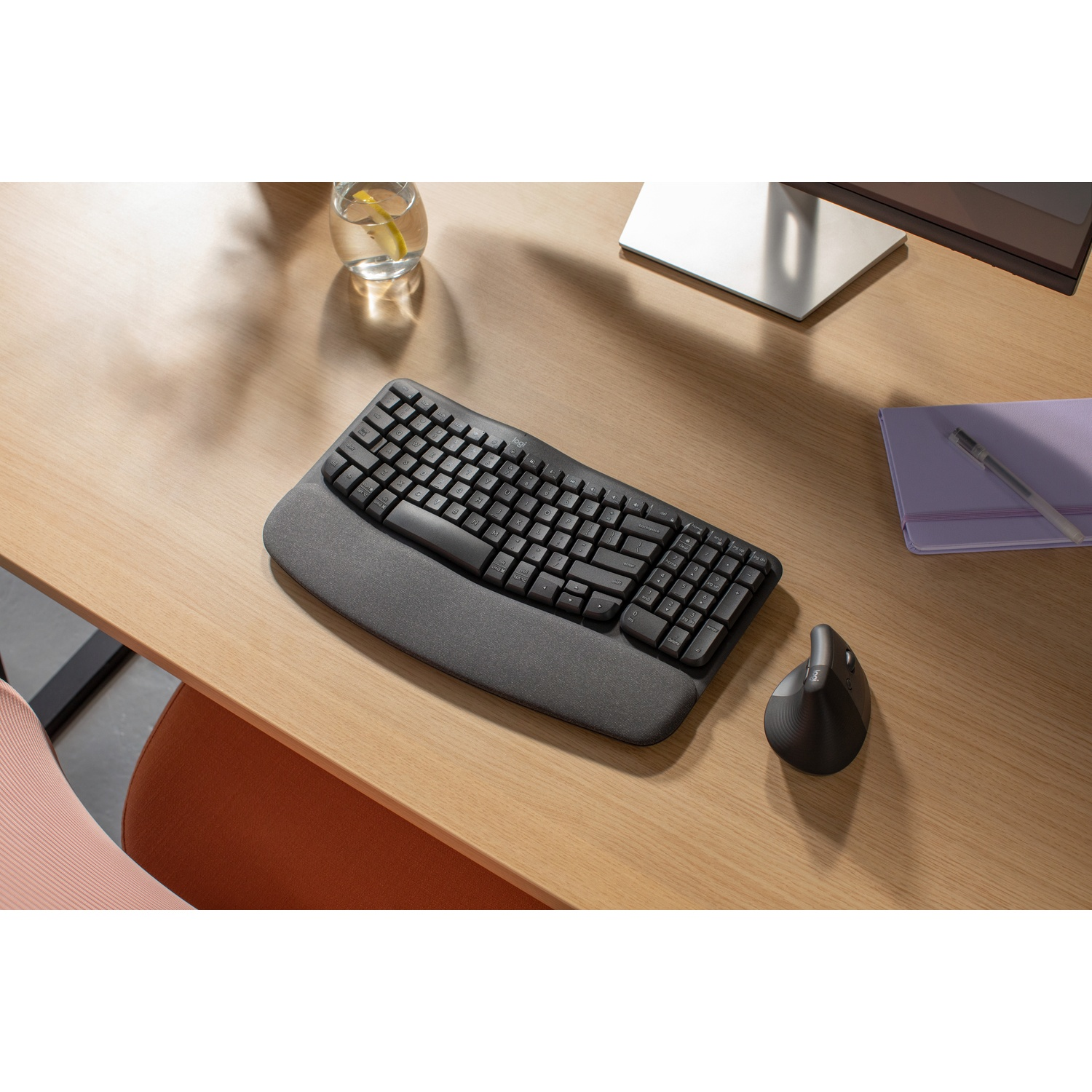 Tastiera ergonomica nera, poggiapolsi e mouse verticale su scrivania in legno.