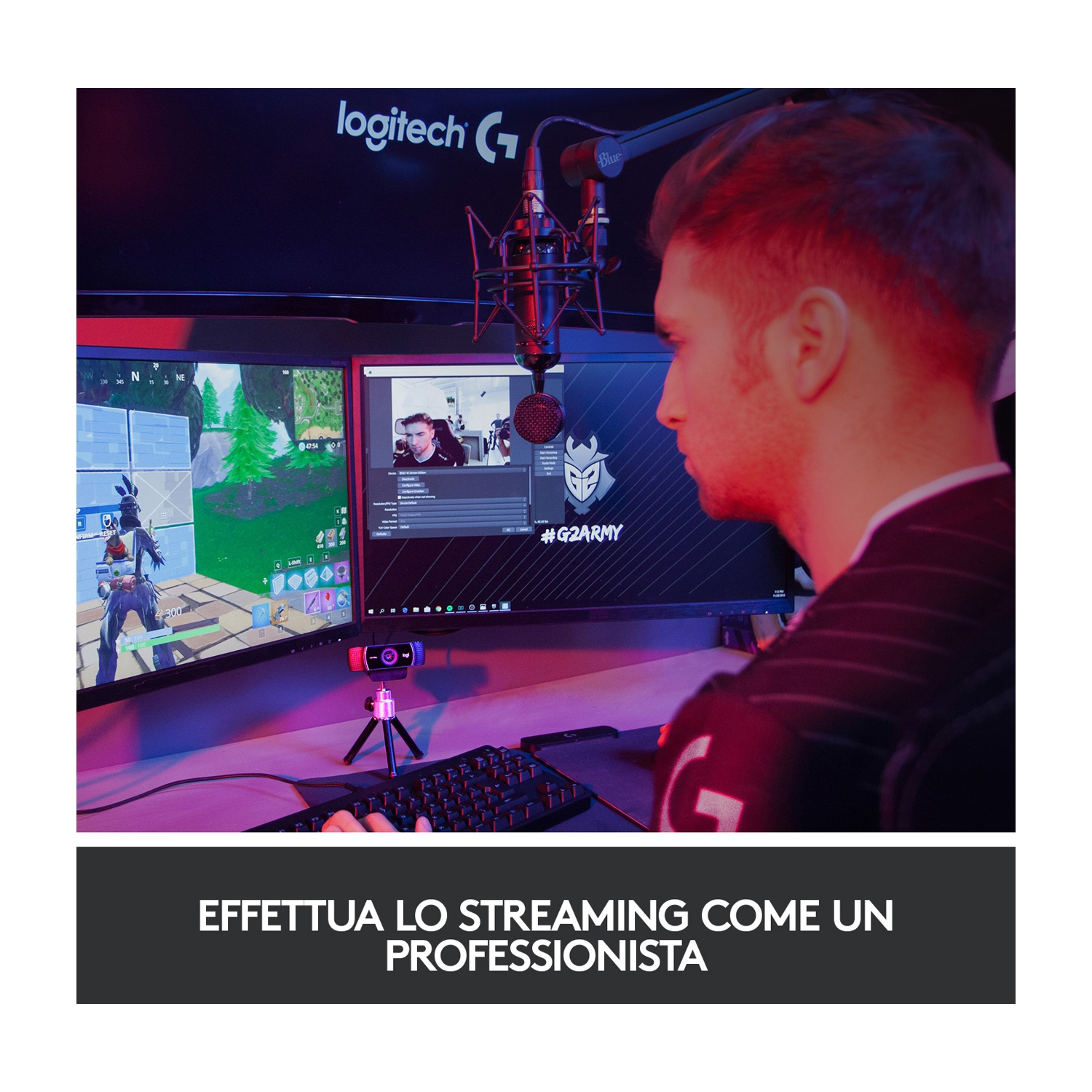 Persona che fa streaming con monitor che mostra gioco e webcam, tastiera nera visibile.