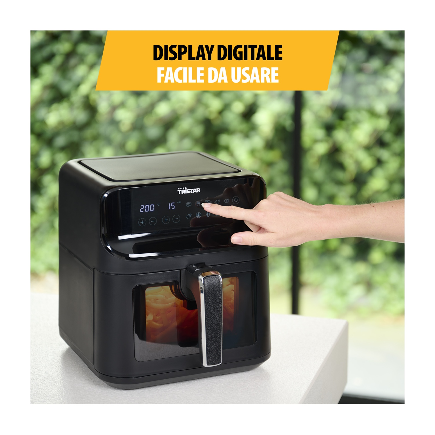 Friggitrice ad aria nera su un tavolo, azionata da una mano.