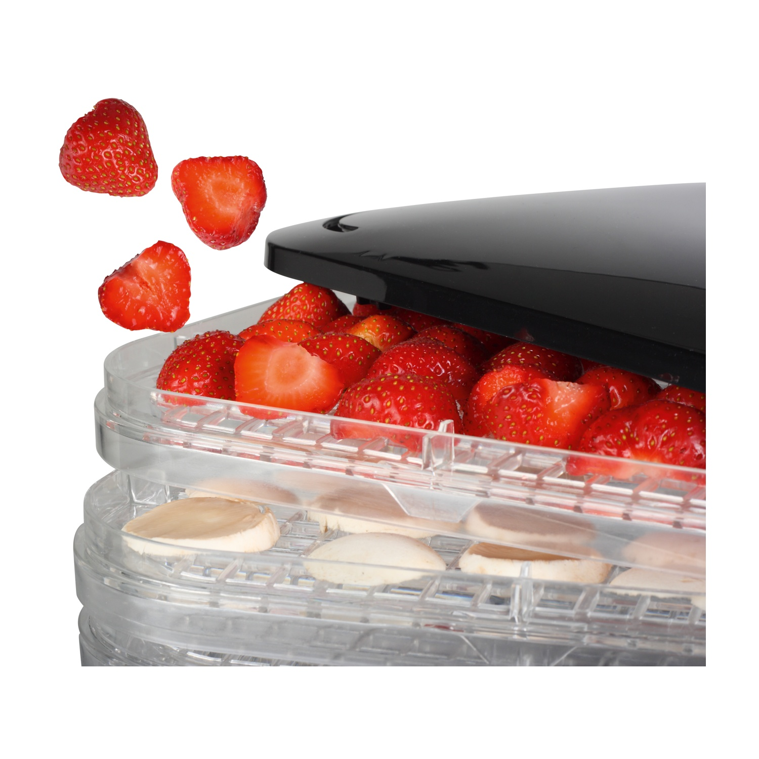 Un primo piano di un essiccatore alimentare con fragole nei vassoi. Alcune fragole cadono.