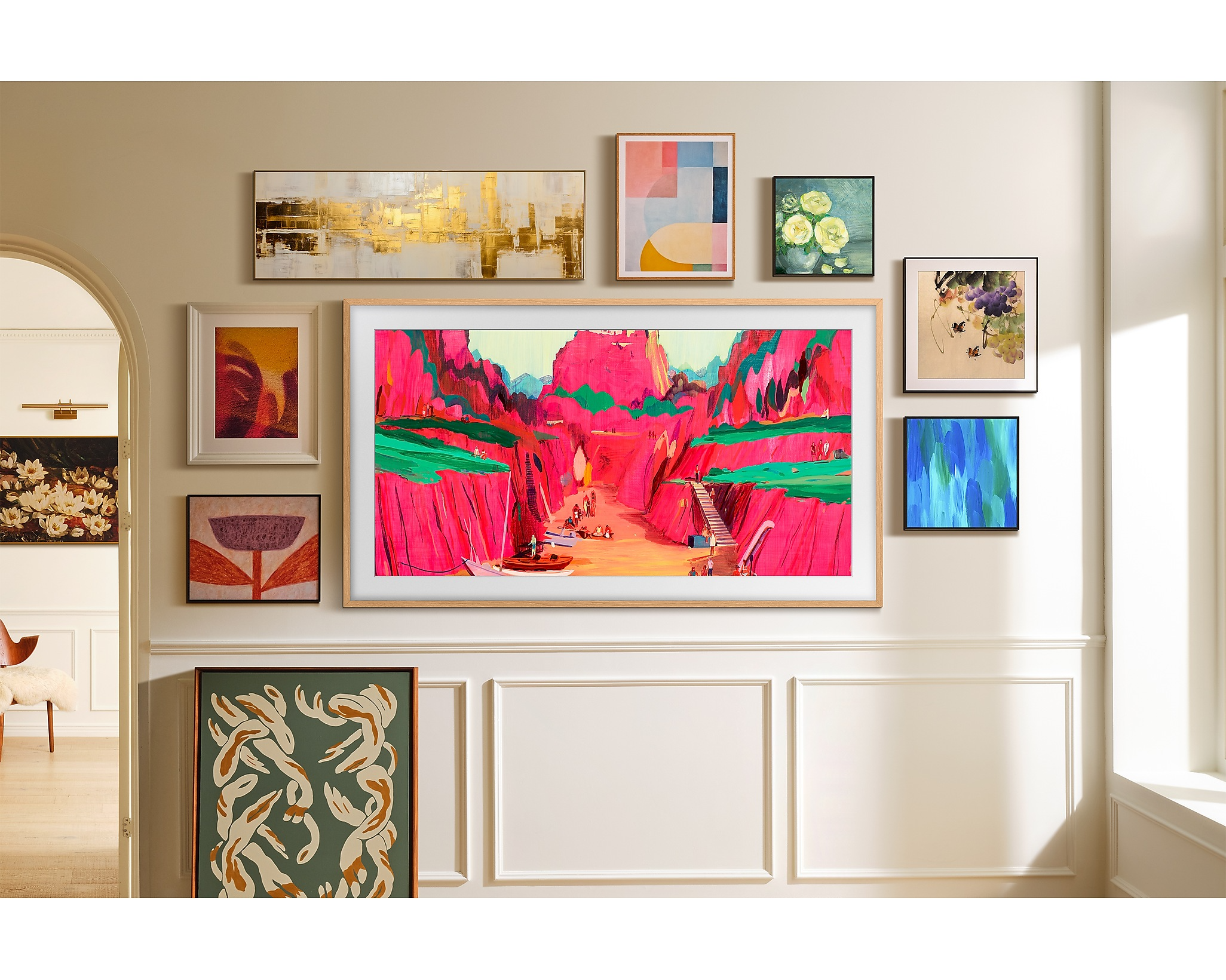 Egy TV műalkotásokkal, más bekeretezett műalkotásokkal körülvéve a falon.