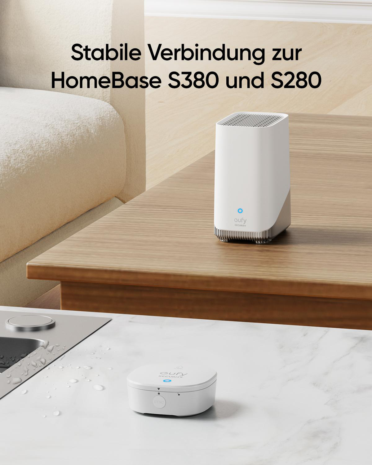 Weißer eufy Wassersensor und eine weiße Basisstation auf einem Holztisch. Im Hintergrund ein weißes Sofa.