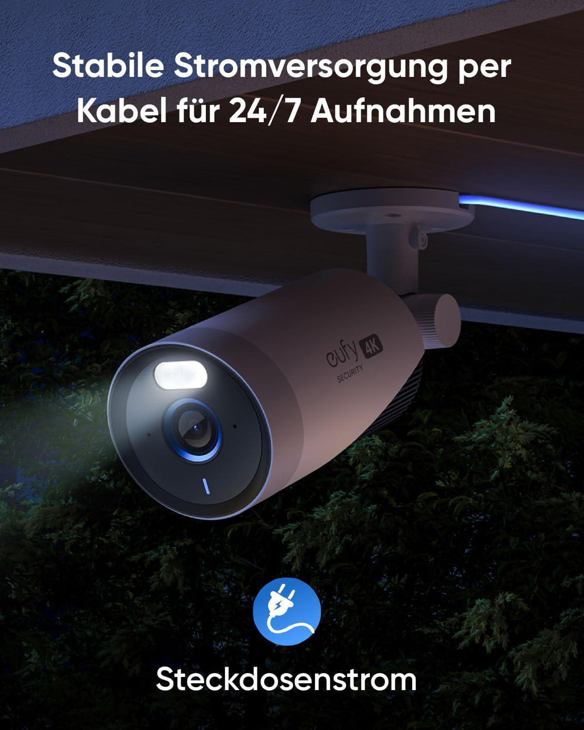 Sicherheitskamera an der Wand montiert, zeigt in der Nacht auf einen Wald mit hellem Licht.