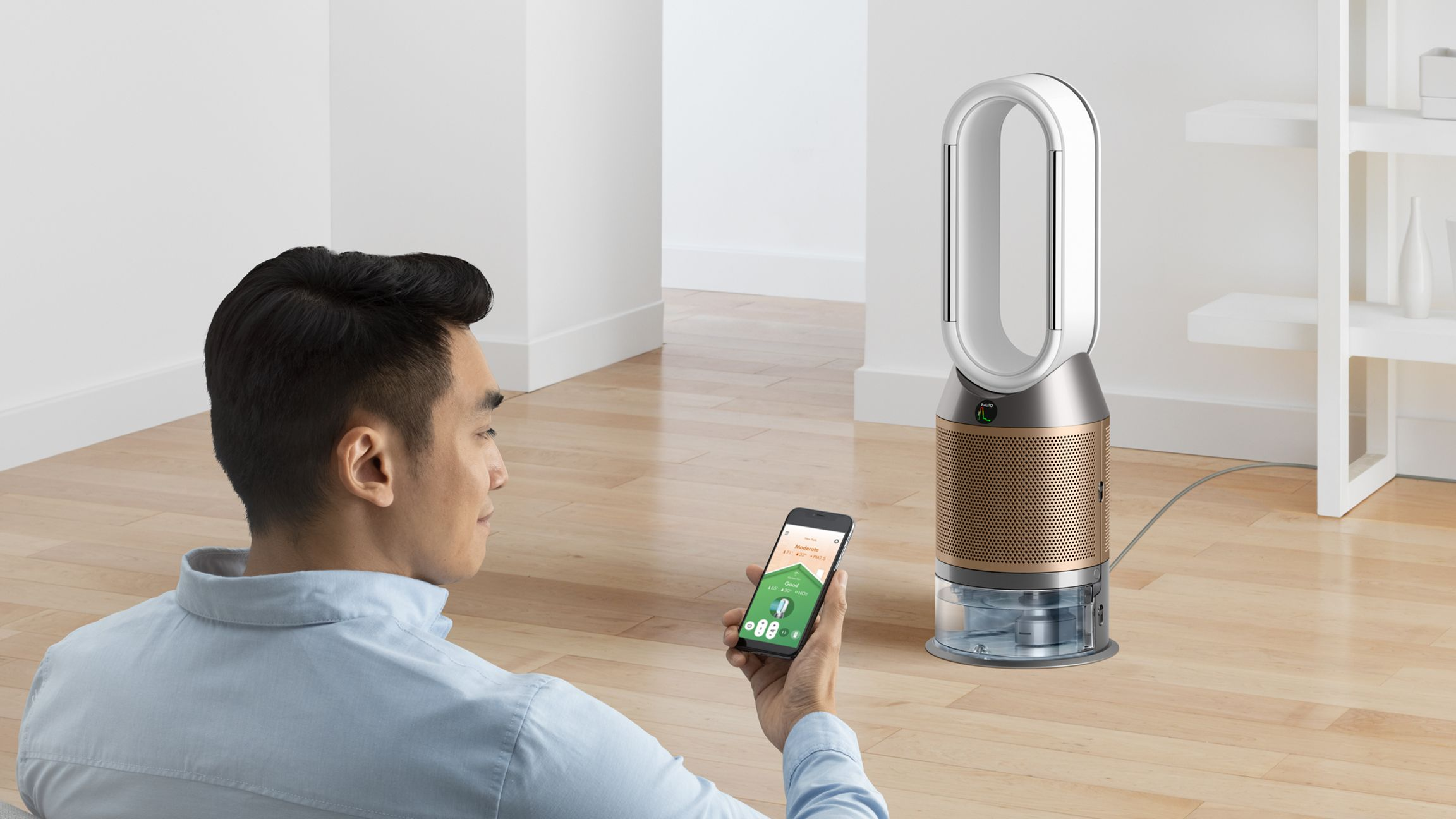 Homme avec smartphone à côté d'un humidificateur Dyson sur parquet.