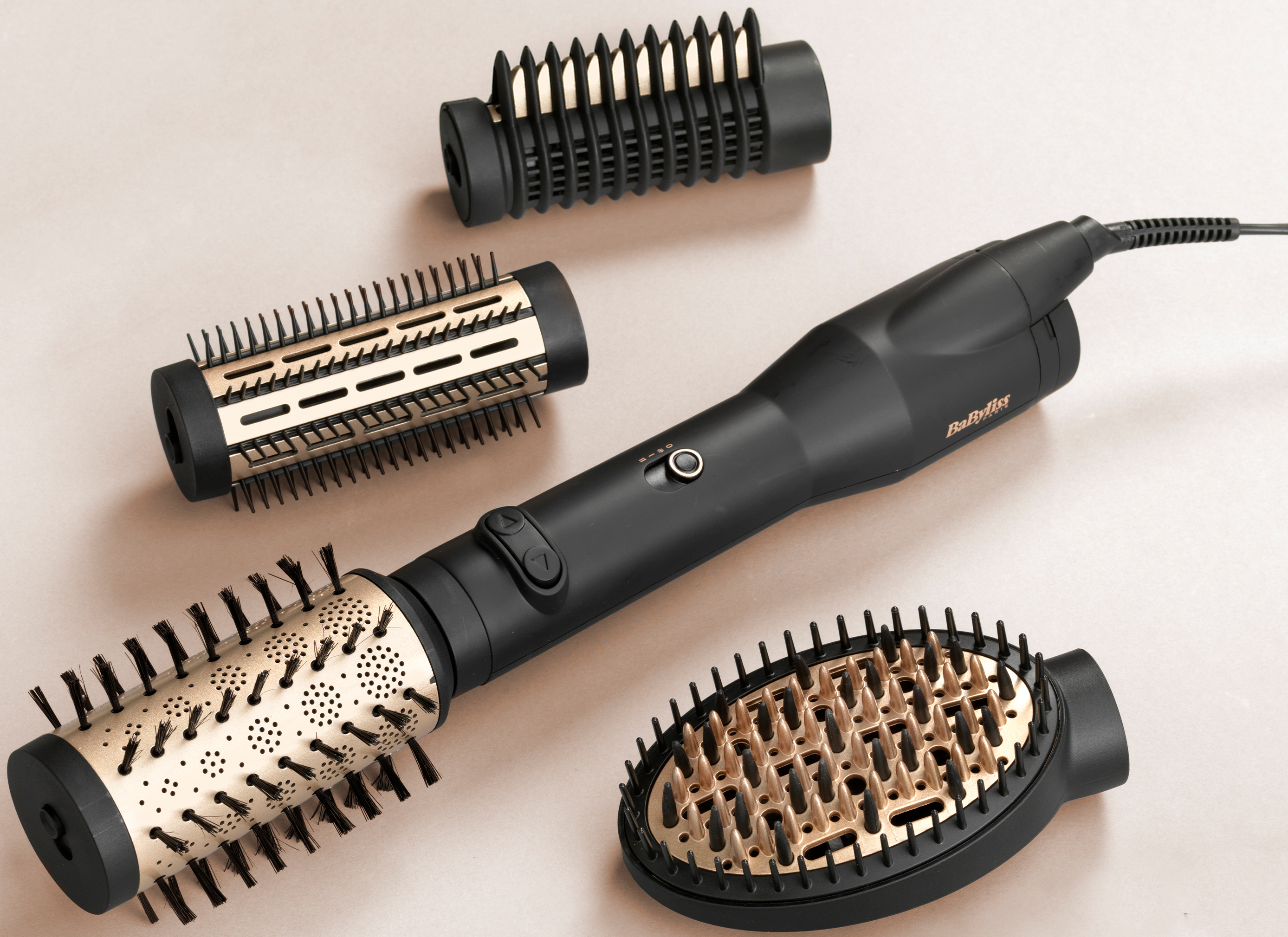 Un ferro arricciacapelli nero con vari accessori su sfondo beige.