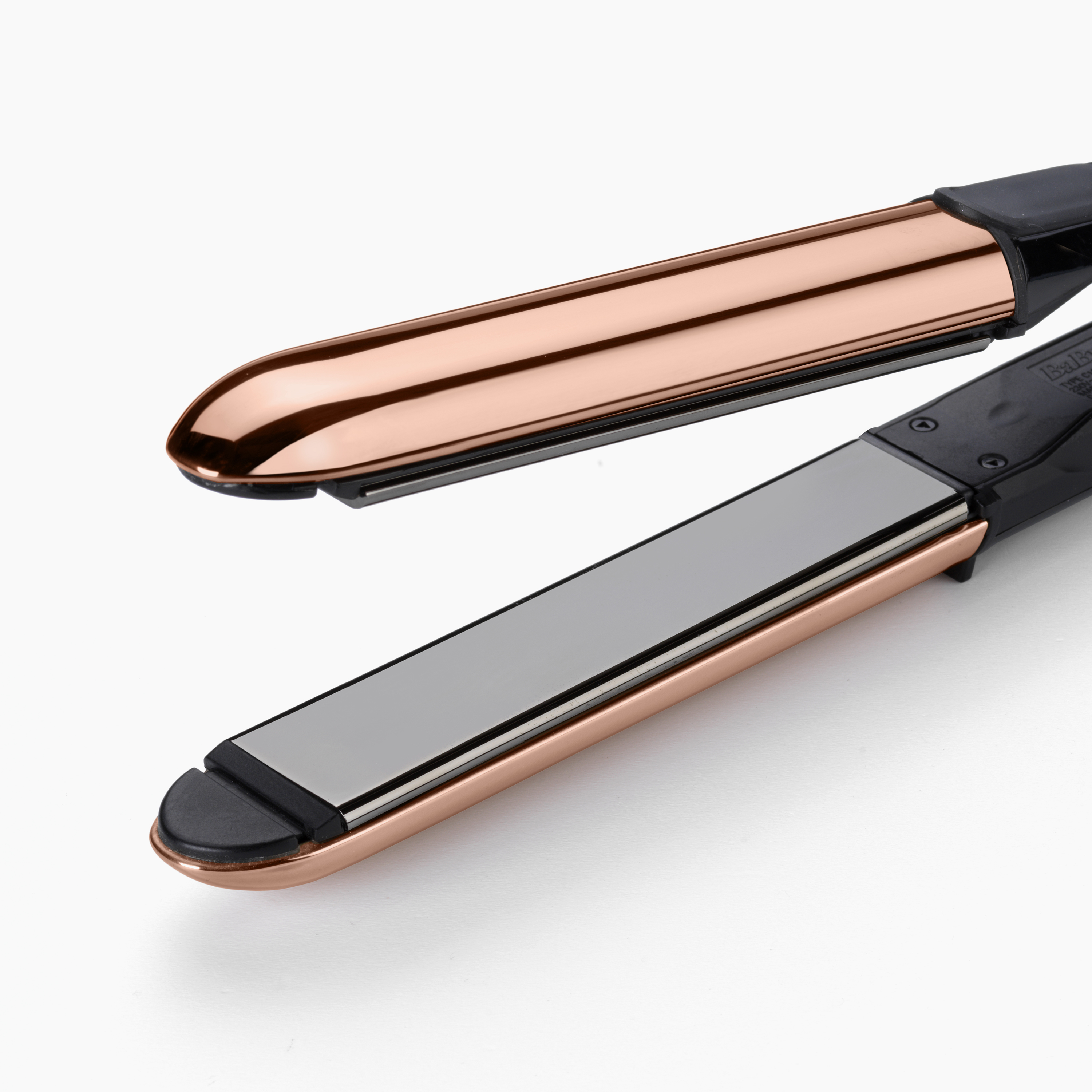 Primo piano di una piastra per capelli aperta in oro rosa su sfondo bianco.