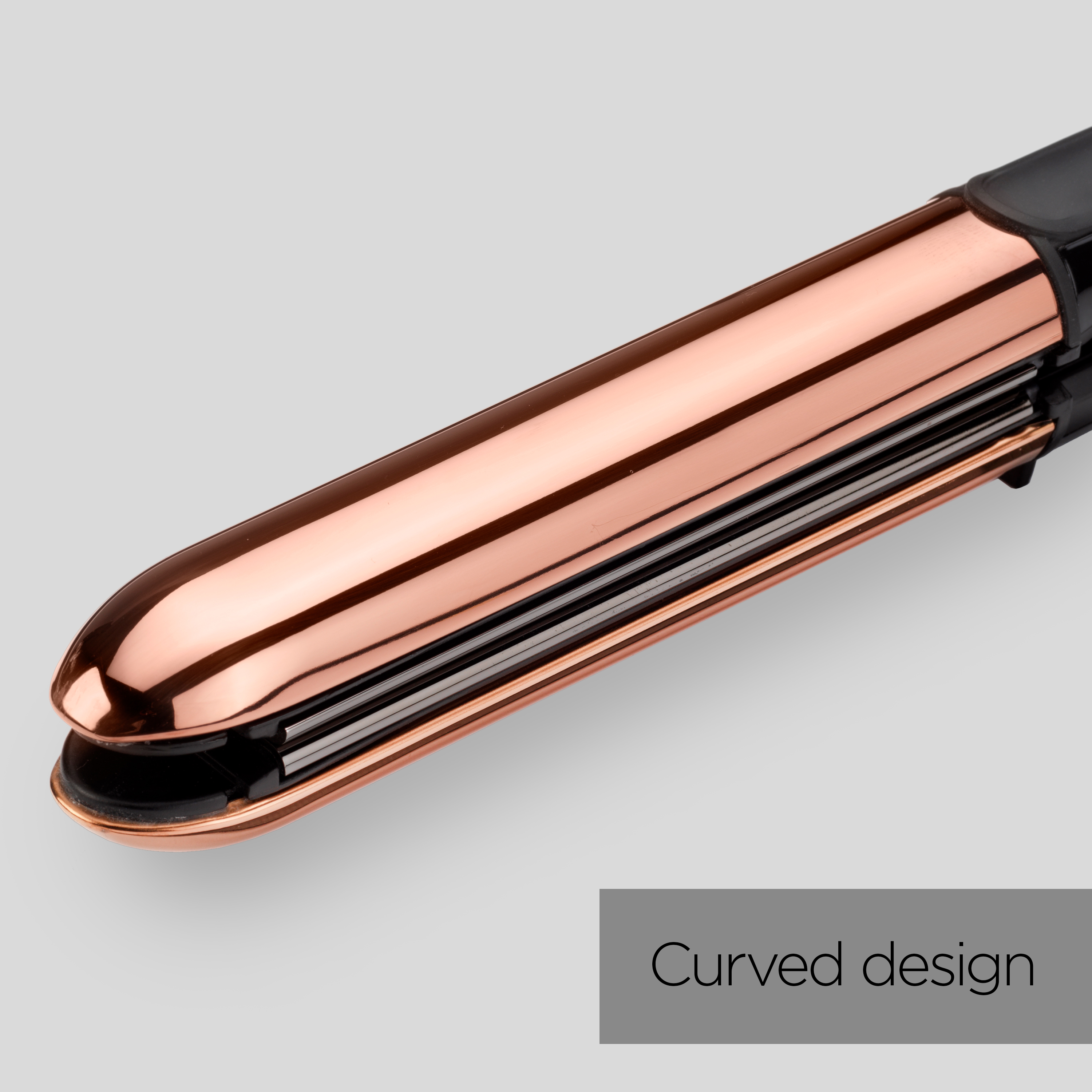 Primo piano di una piastra per capelli in oro rosa su uno sfondo grigio.