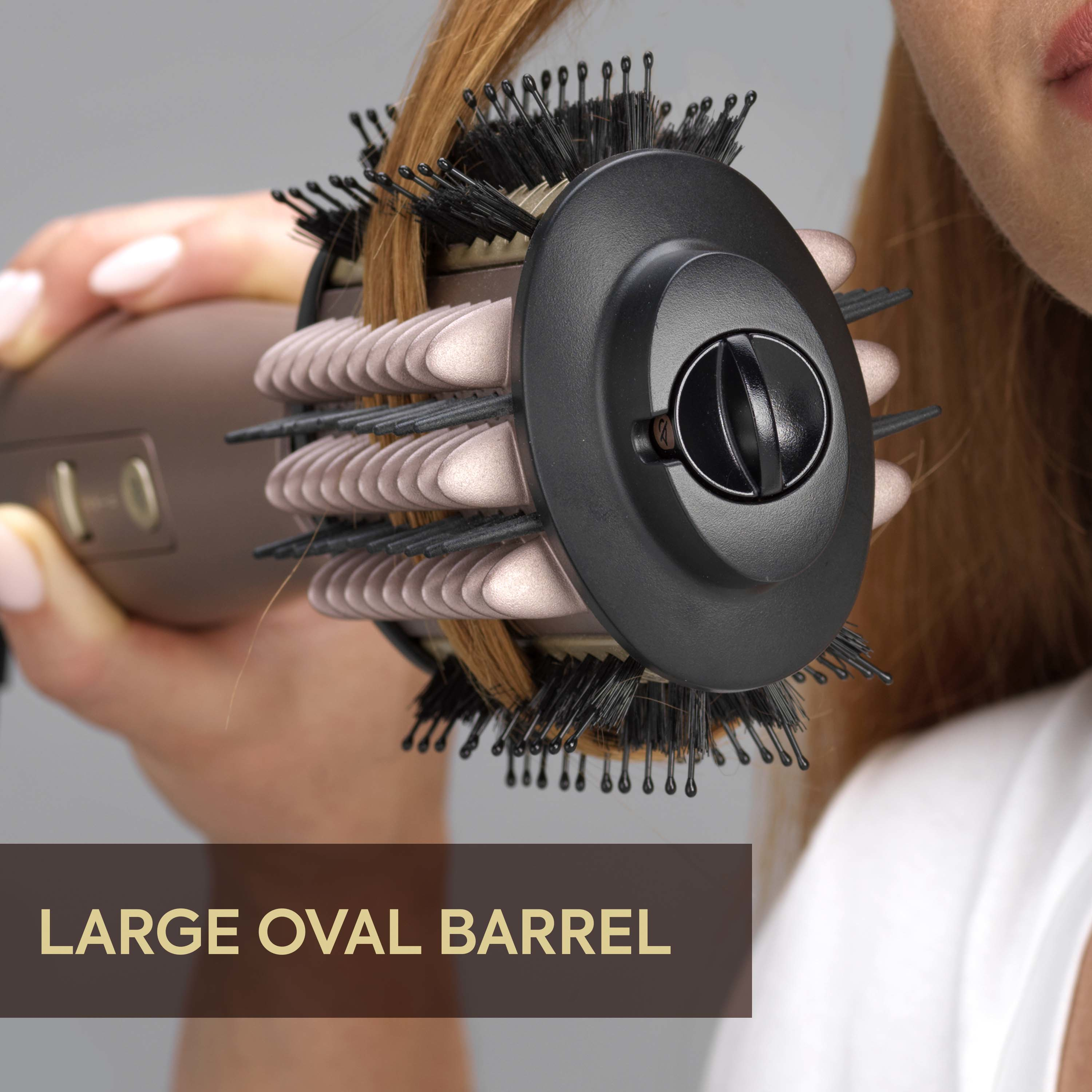 Primo piano di una donna che si acconcia i capelli rossastri con una spazzola rotonda marrone con setole nere.