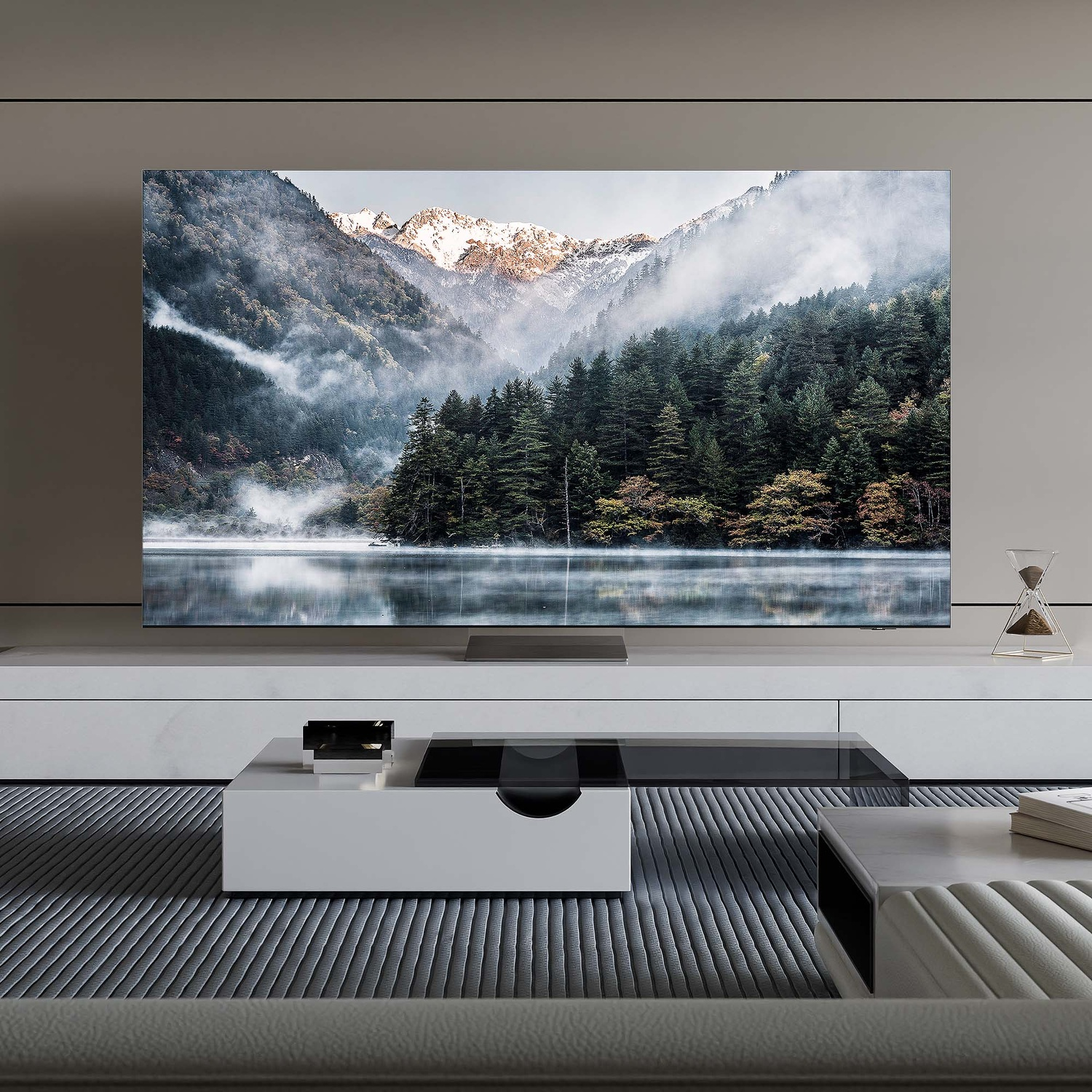 Una TV mostra una vista panoramica sulle montagne con un lago calmo e alberi nebbiosi.