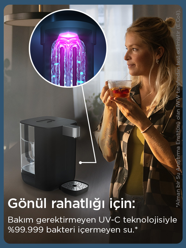 Bir kadın, UV-C teknolojisine sahip bir su arıtma cihazının yanında bir fincan tutuyor.