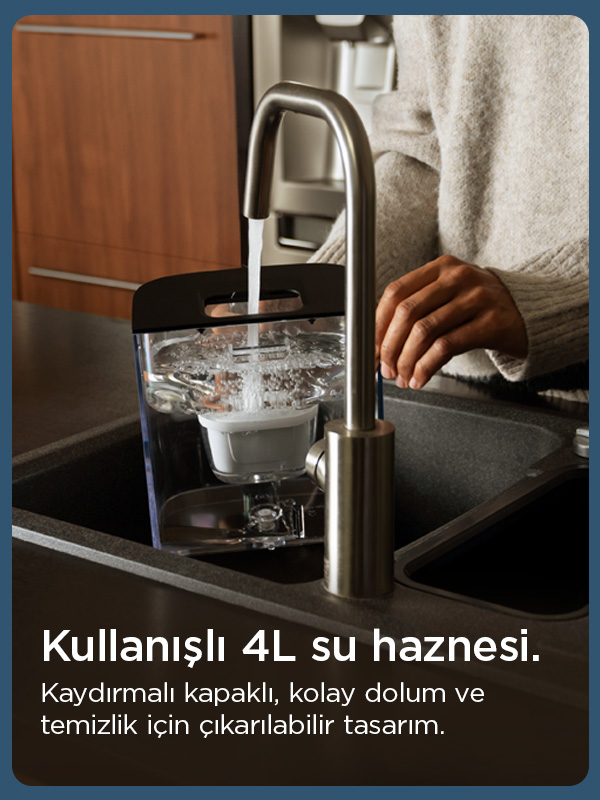 Bir kişi, koyu renkli bir lavaboda gümüş bir muslukla şeffaf bir su deposunu dolduruyor.