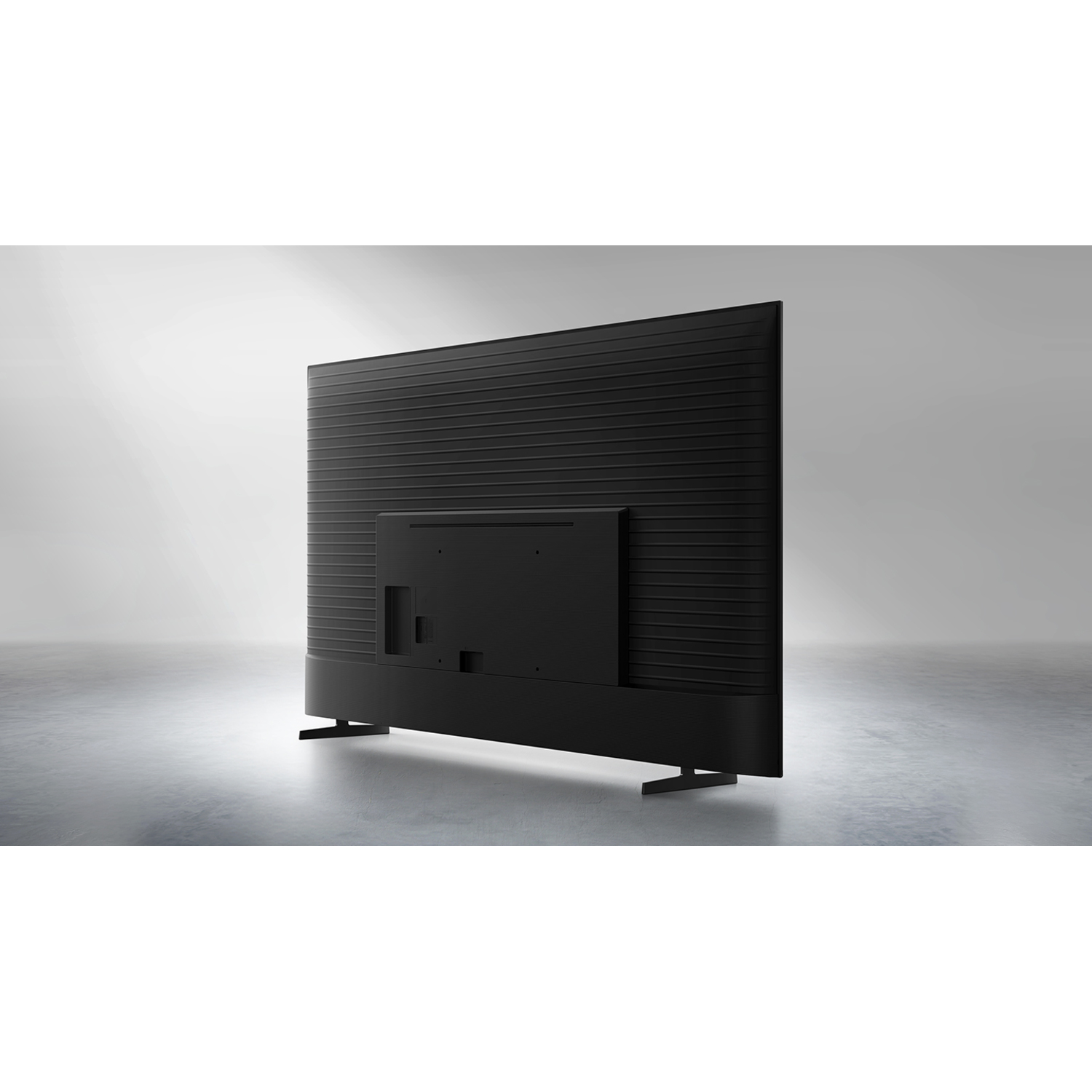 Back view of a black TV on a gray floor against a gray background.