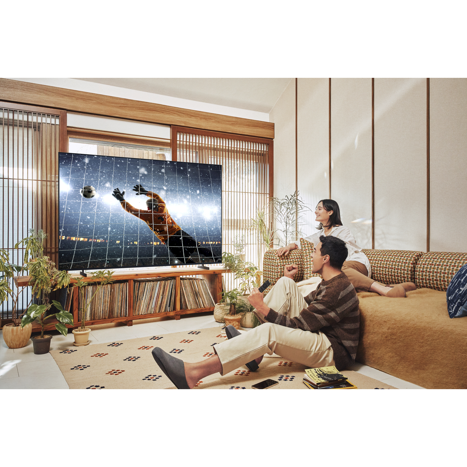 A couple watches a soccer game on a large TV in a cozy living room.