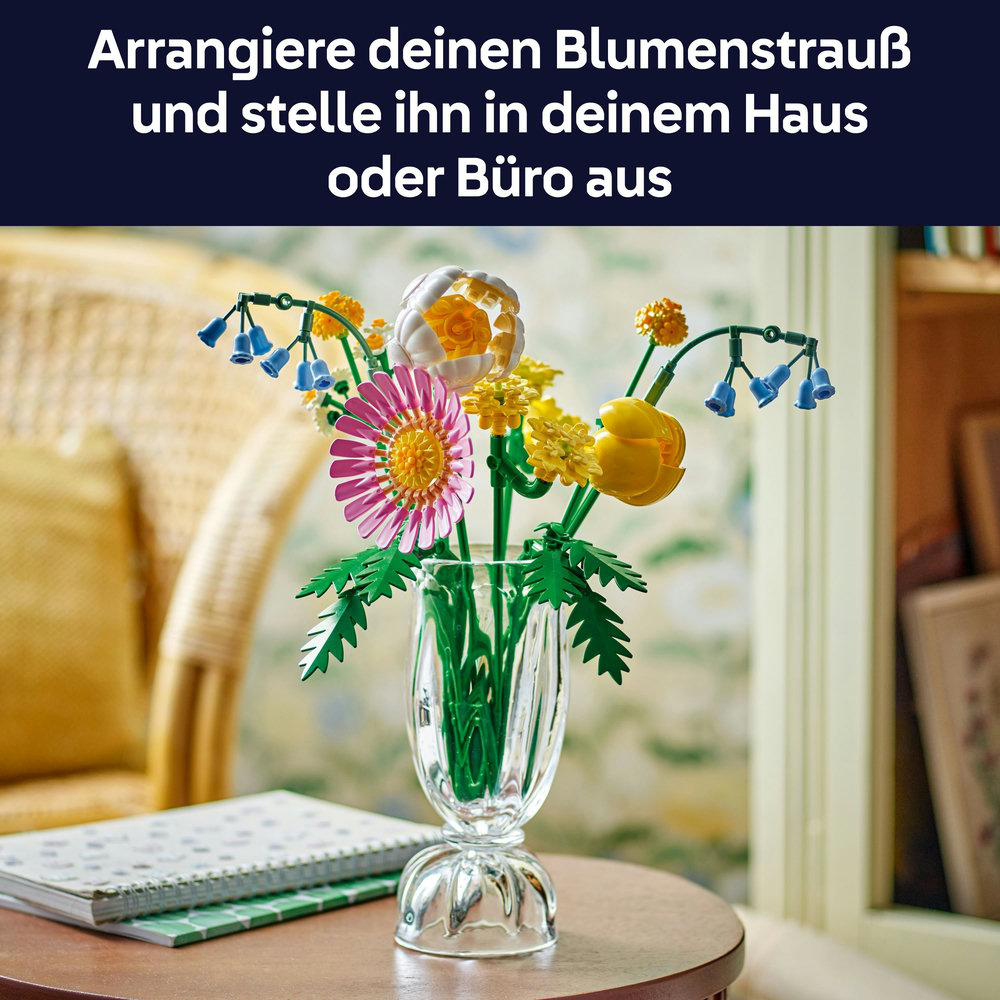 Ein Blumenstrauß aus Lego-Steinen in einer Vase auf einem Tisch, daneben ein Notizbuch.