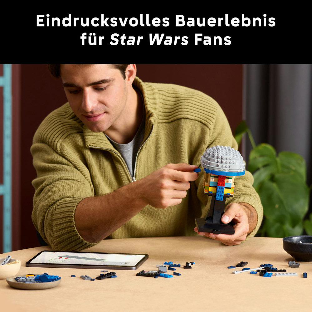 Mann baut ein Lego-Set mit grauen, blauen und bunten Teilen auf einem Tisch.