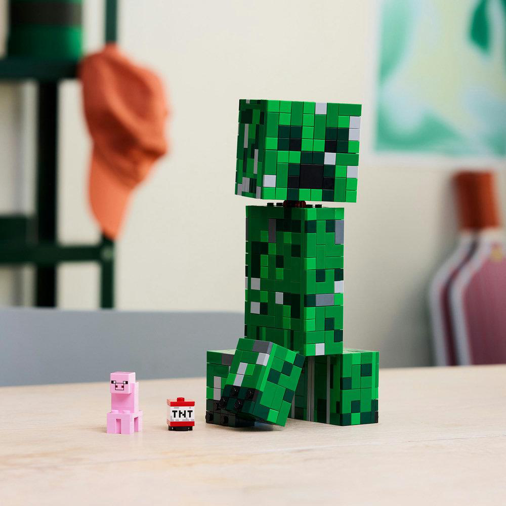 Ein Lego Minecraft Creeper steht neben einem Schwein und TNT auf einem Tisch.