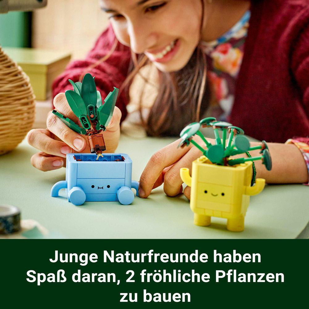 Junge Frau baut Lego-Pflanzen in blauen und gelben Töpfen.