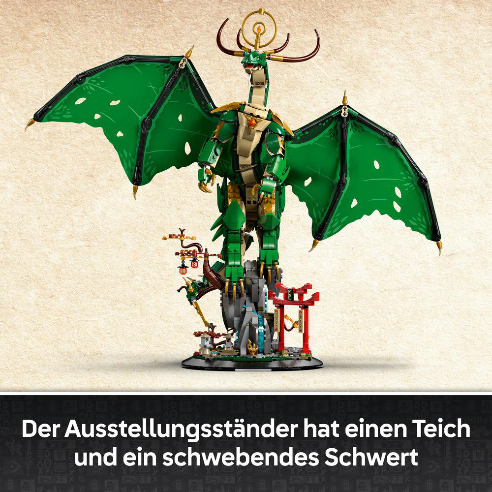 Ein grüner Lego-Drache mit goldenen Akzenten steht auf einem Ausstellungsstand mit Teich und schwebendem Schwert.