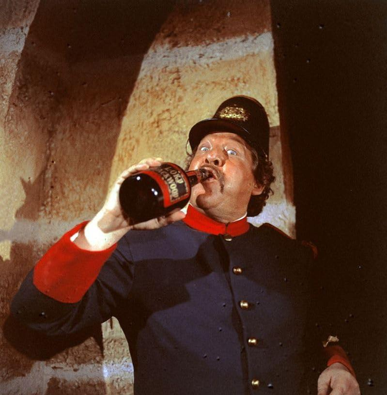 Ein Mann in Uniform trinkt aus einer Flasche, die Flasche trägt die Aufschrift 'Lord Stathum'.