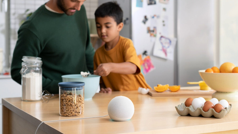 Ojciec i syn pieką w kuchni z głośnikiem smart na blacie.