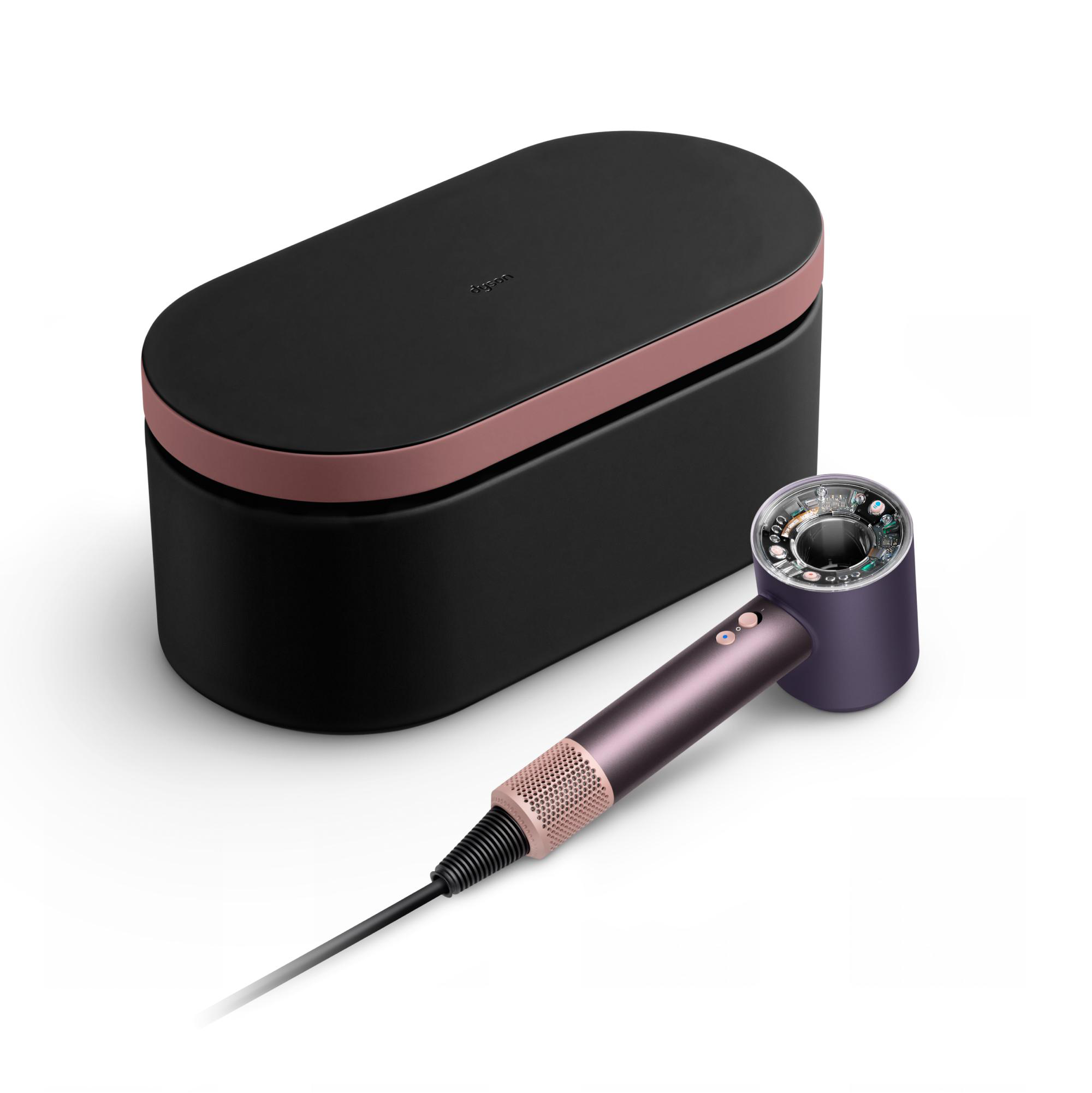 Ein Dyson-Haartrockner und seine schwarz-roségoldene Hülle liegen auf einer weißen Oberfläche.