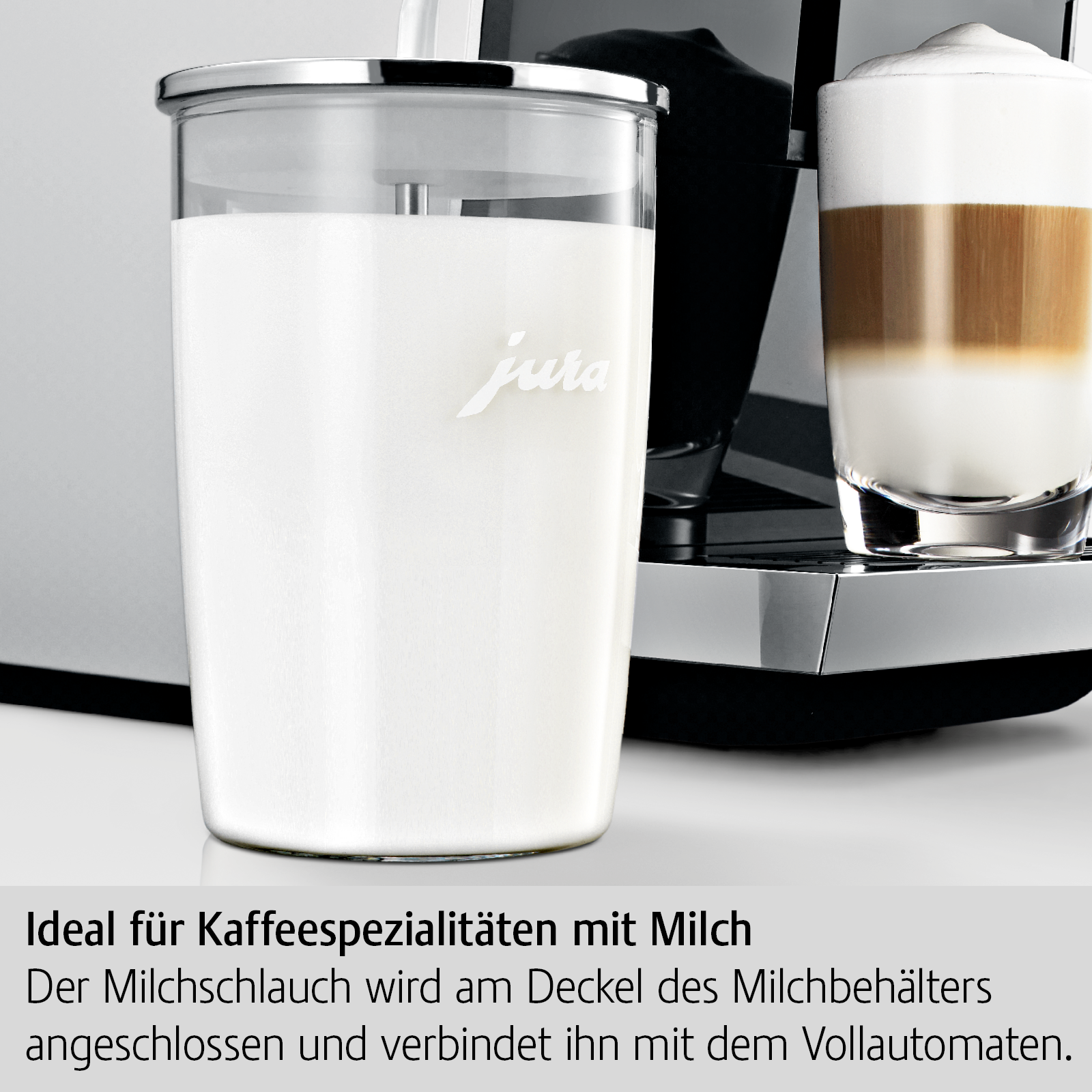 Ein Milchbehälter mit Milch, neben einer Kaffeemaschine mit einem Glas Latte Macchiato.