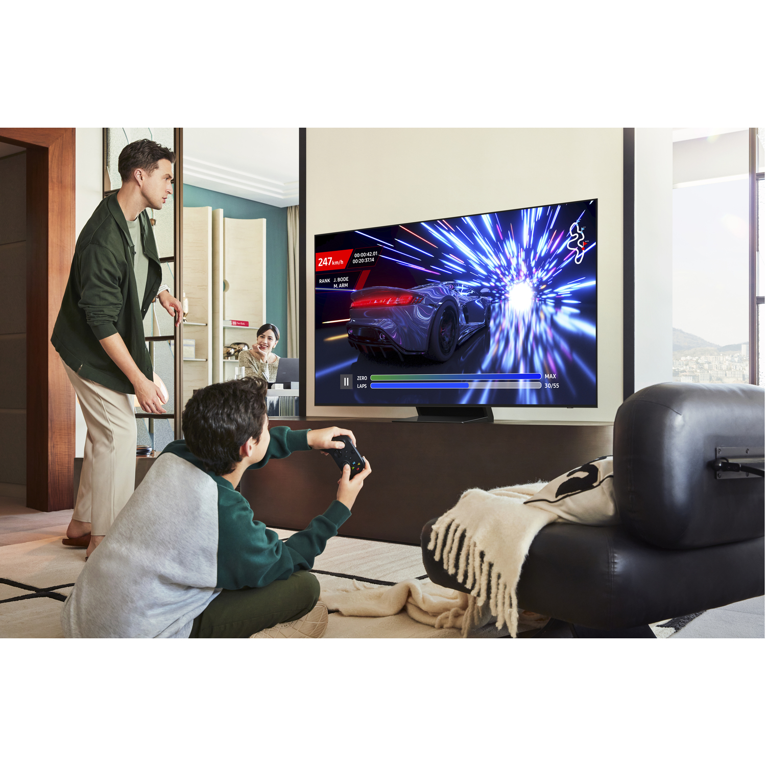 Garçon jouant à un jeu vidéo, homme regardant, grande TV montrant un jeu de course.