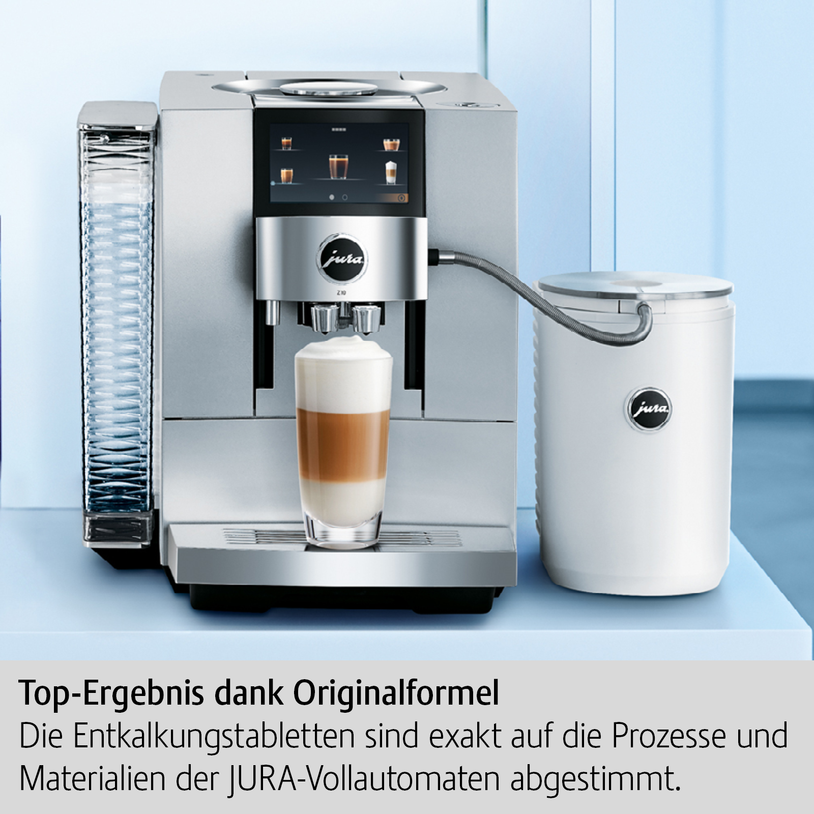 Silberne Jura Kaffeemaschine mit Latte Macchiato, neben weißem Behälter, auf blauem Regal.