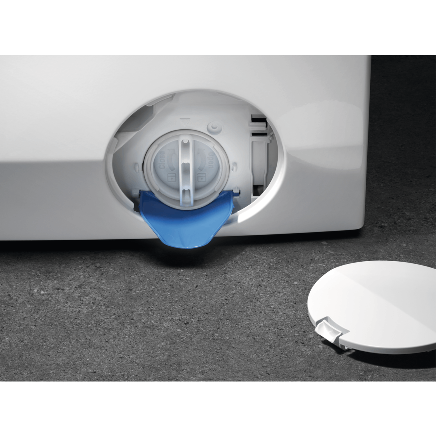 Close-up of a washing machine drain. It shows the blue closure and the white cover next to it.