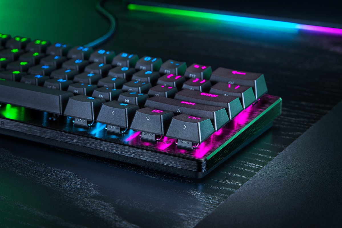 Zbliżenie podświetlanej klawiatury. Klawisze są czarne z kolorowym podświetleniem. Widoczne logo Razer.