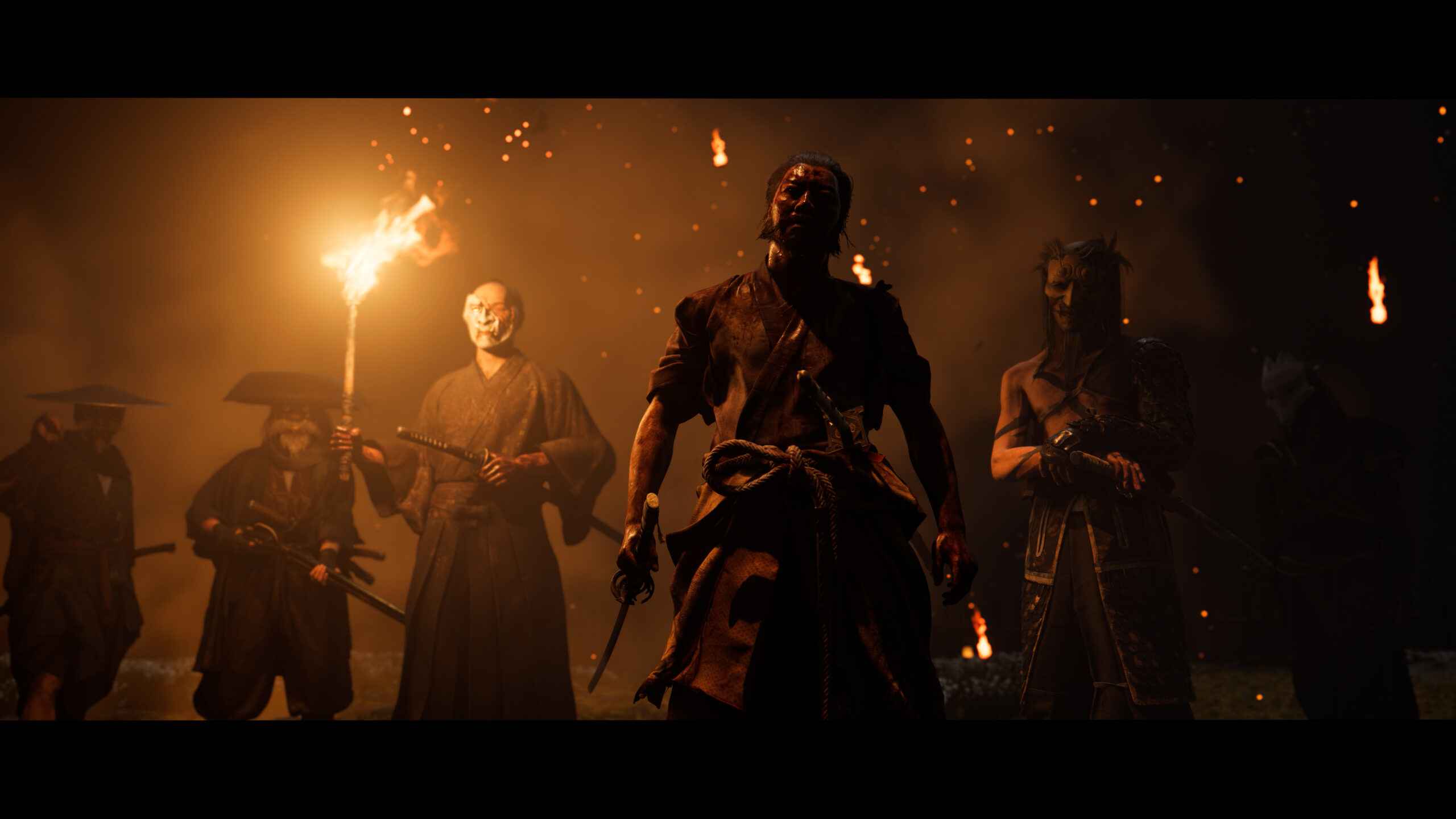 Un gruppo di samurai con spade e torce in un ambiente buio.