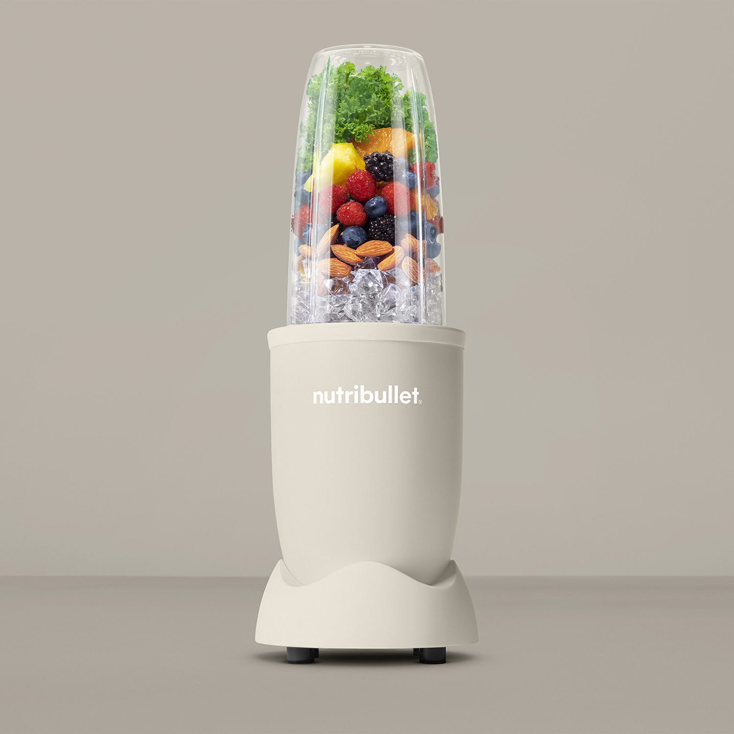 A cream-colored Nutribullet blender with fruits and ice cubes, on a light gray background.