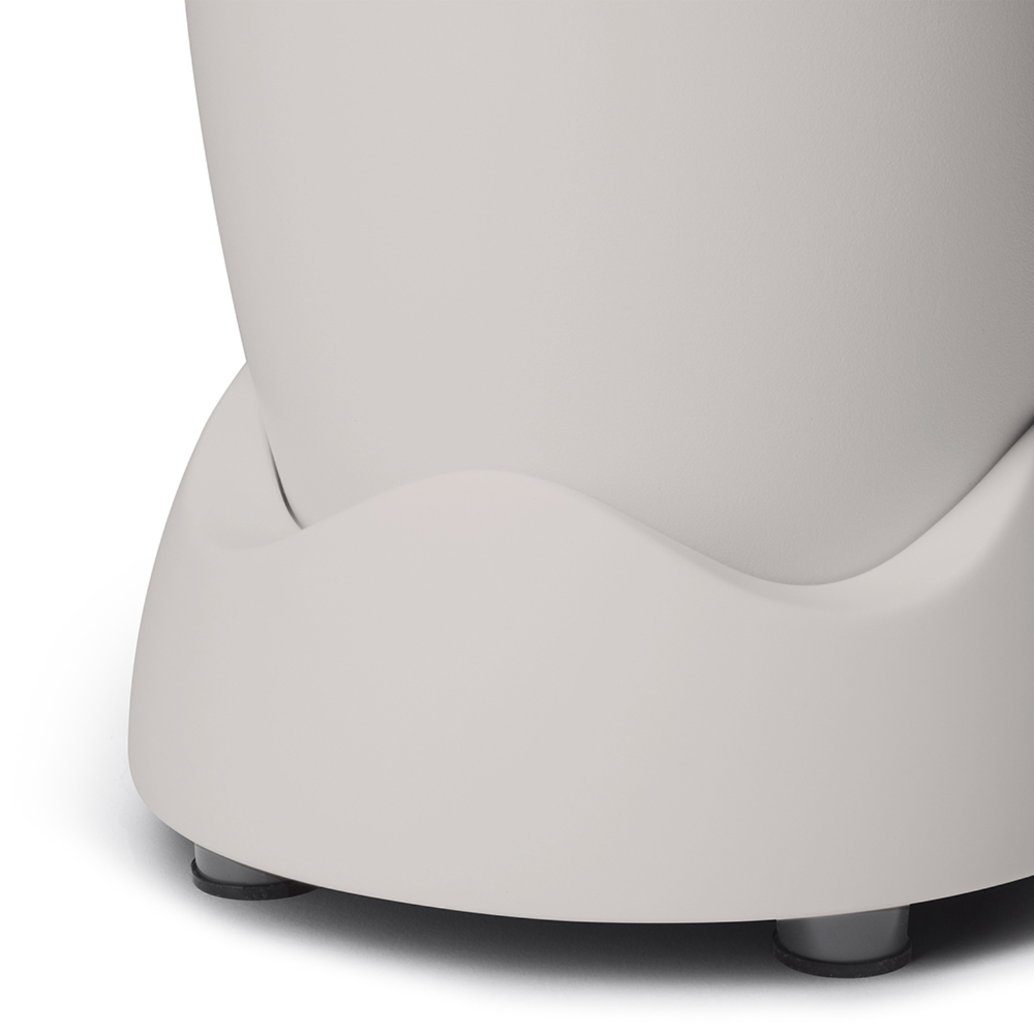 Close-up of the base of a blender. The base is light beige with black rubber feet.