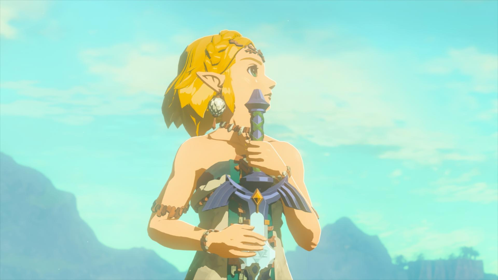 Eine Frau mit blondem Haar hält ein Schwert. Sie trägt eine Halskette und ein Armband. Der Hintergrund ist ein blauer Himmel.