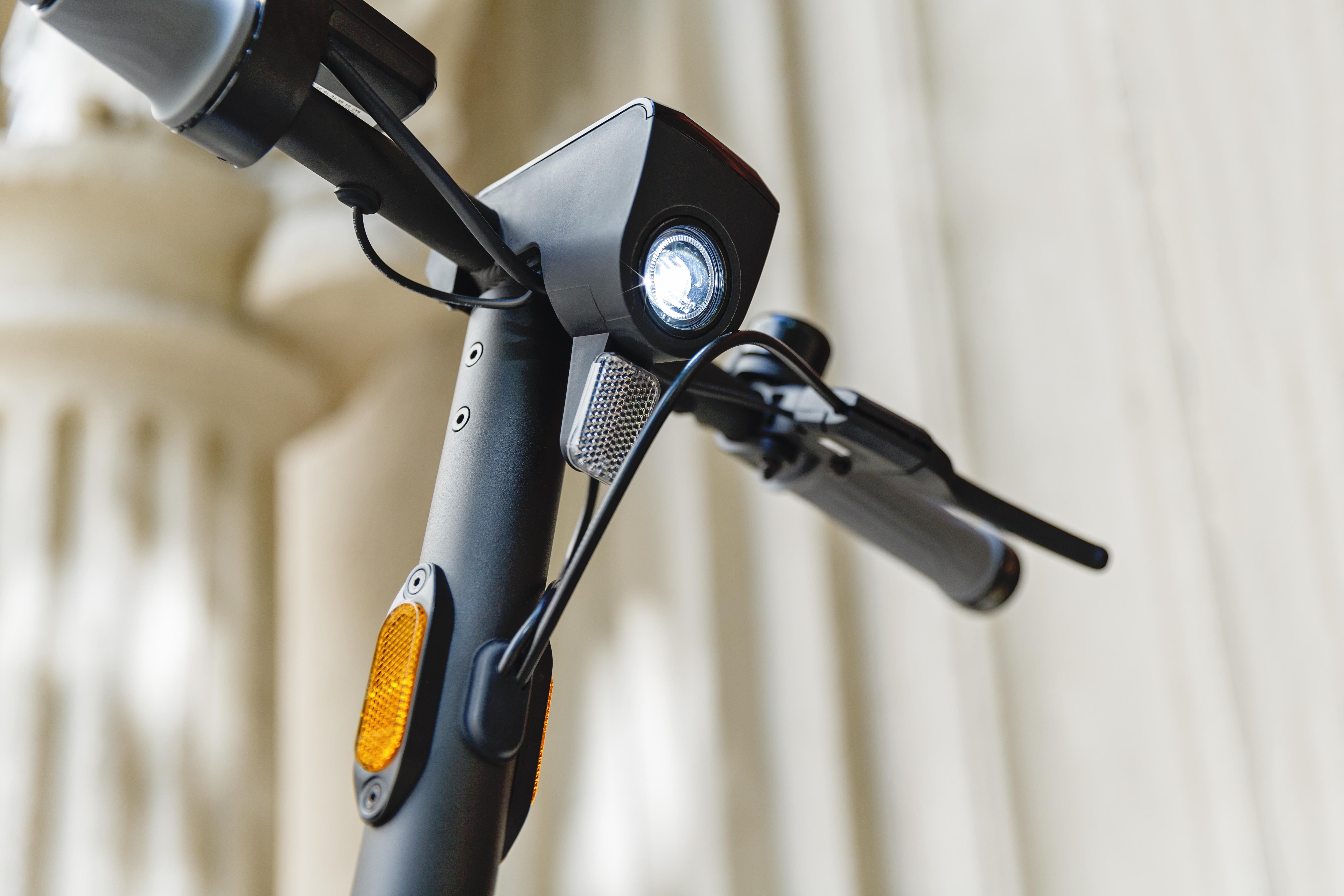 Nahaufnahme des Scheinwerfers eines Elektrorollers mit Reflektor und Blinker.