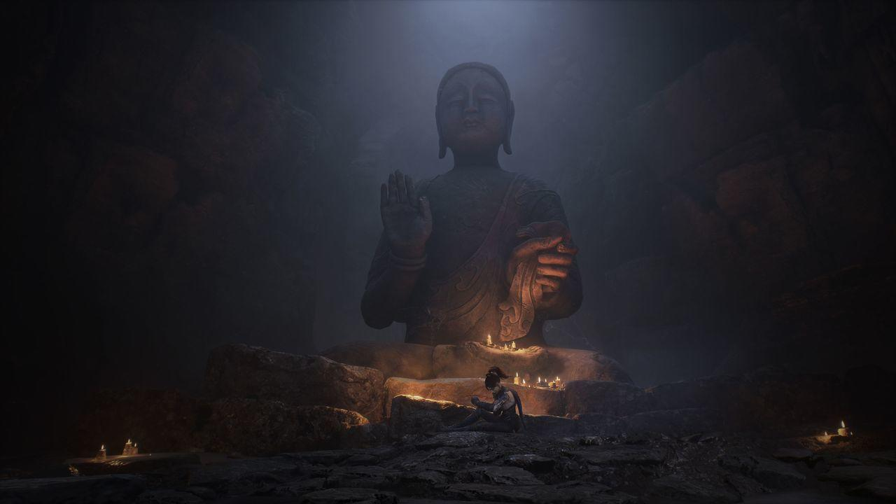 Eine Person sitzt vor einer riesigen Buddha-Statue in einer Höhle. Kerzen und sanftes Licht erhellen die Szene, was eine ruhige Atmosphäre schafft.