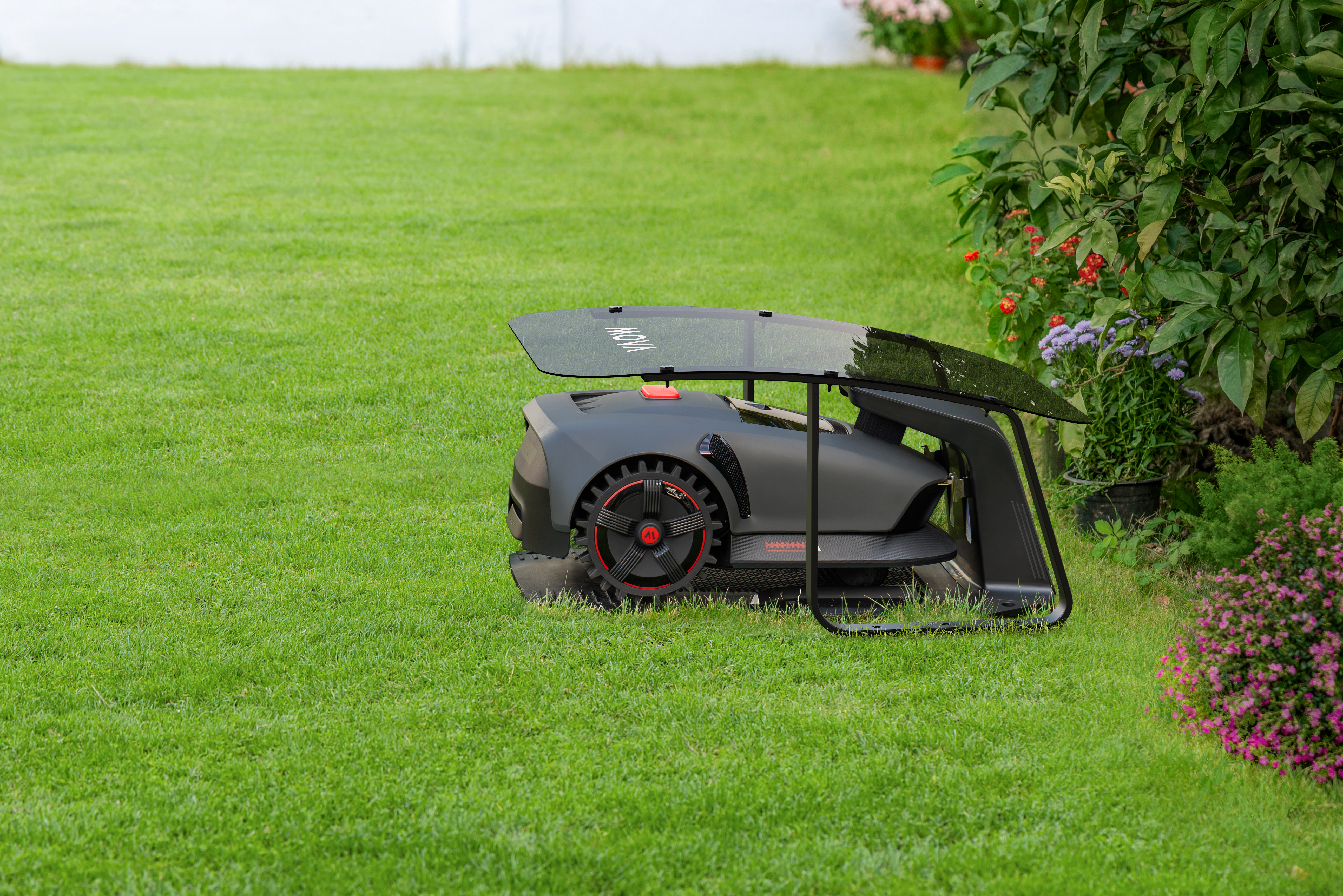 Ein Rasenroboter auf einer grünen Wiese, mit einem Baum im Hintergrund.