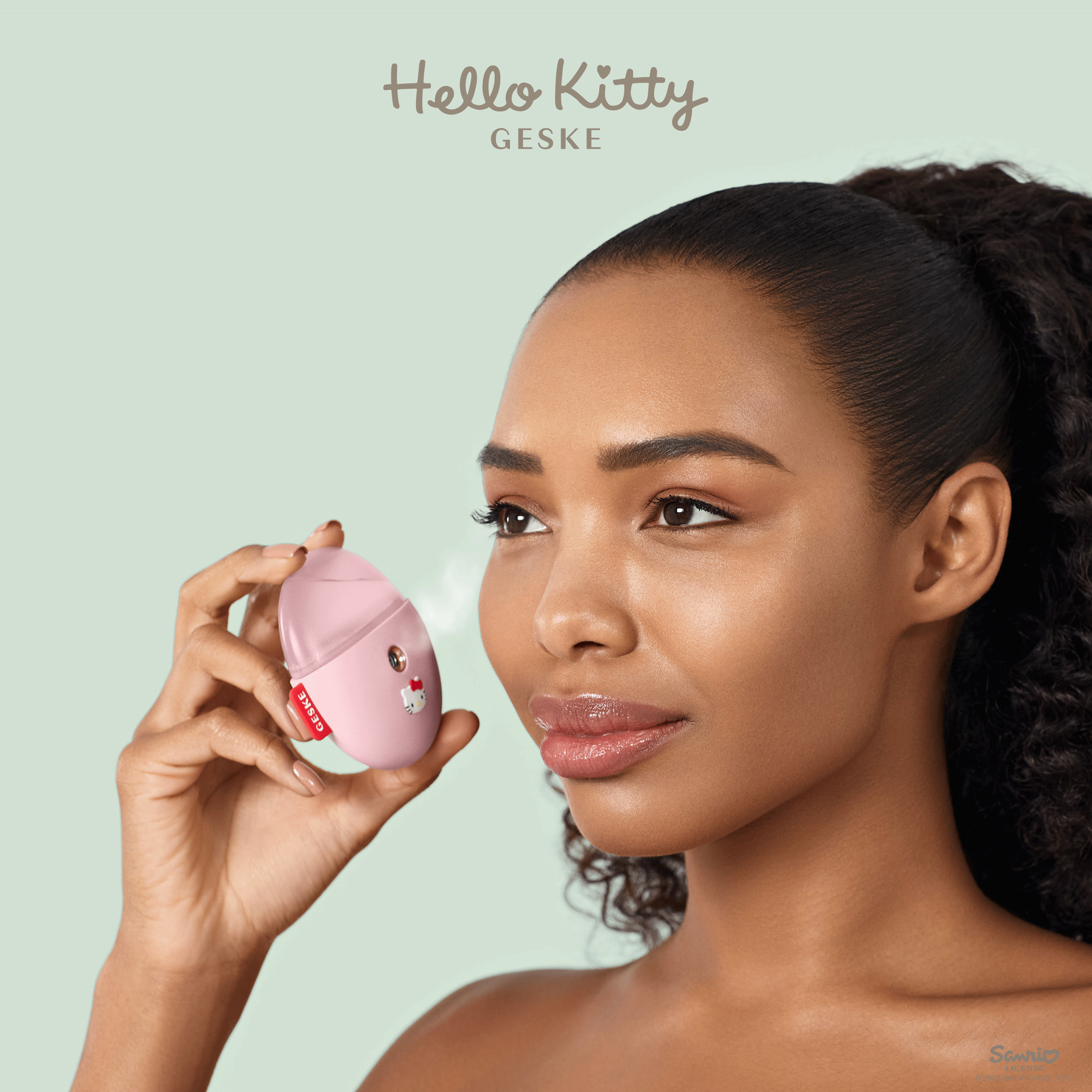 Bir kadın pembe bir Hello Kitty cilt bakım cihazını yüzüne tutuyor. Cihazdan buhar çıkıyor.