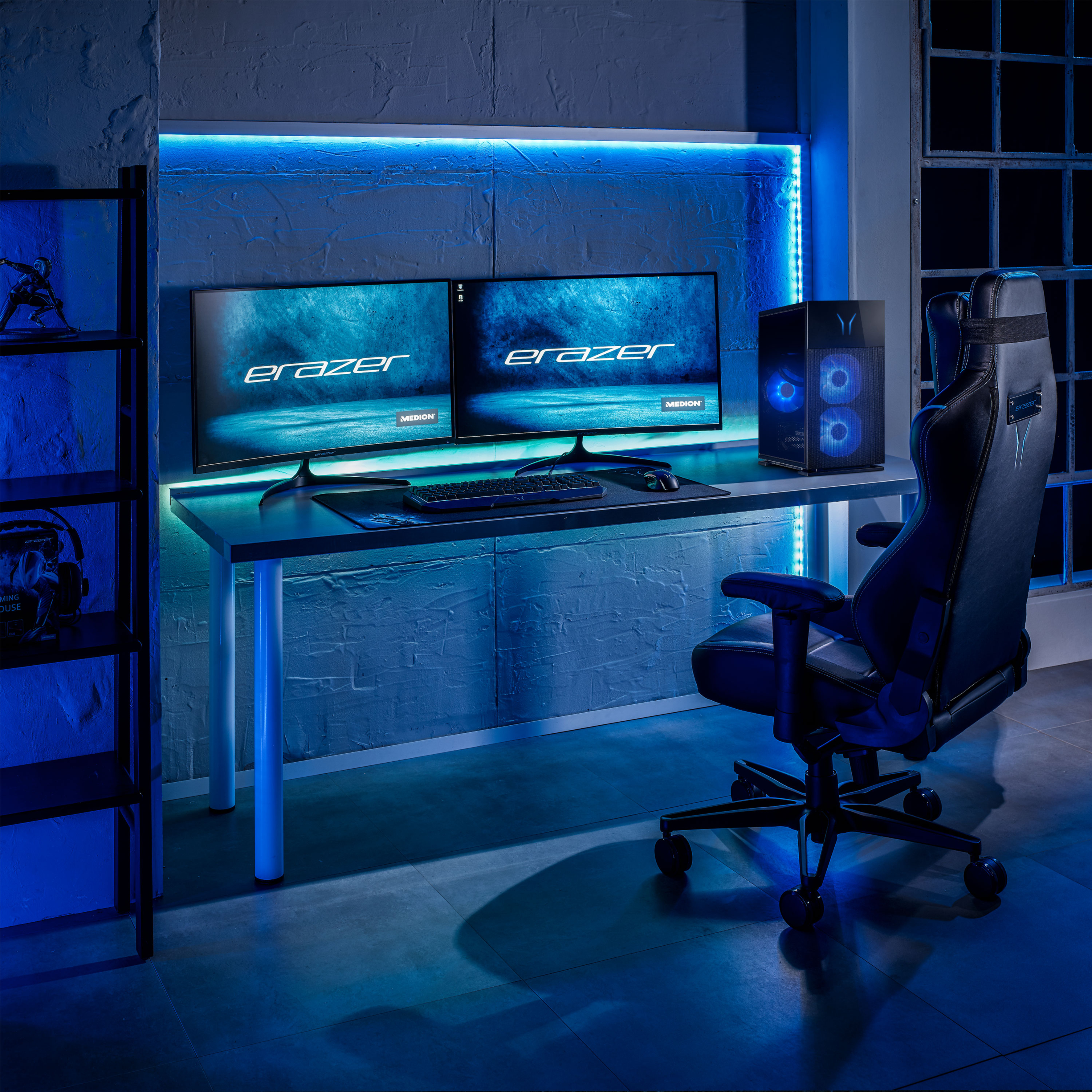 Ein Gaming-Setup mit zwei Monitoren, PC-Tower, Schreibtisch und Stuhl. Blaue LED-Beleuchtung.